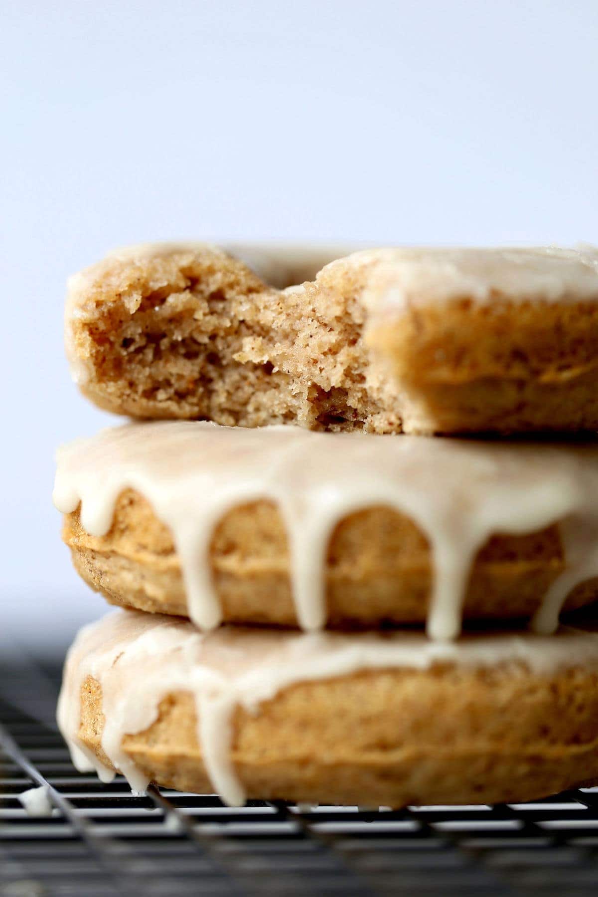 stacked Baked Chai Donuts with glaze on top that has a bite