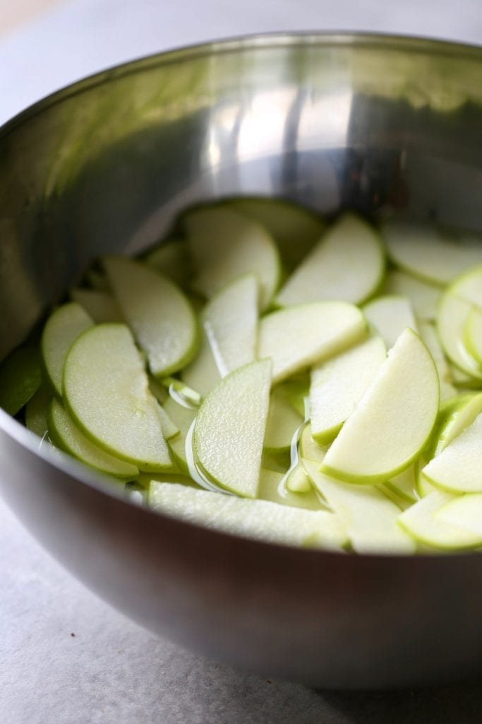 sliced granny smith apples soaking in lemon water