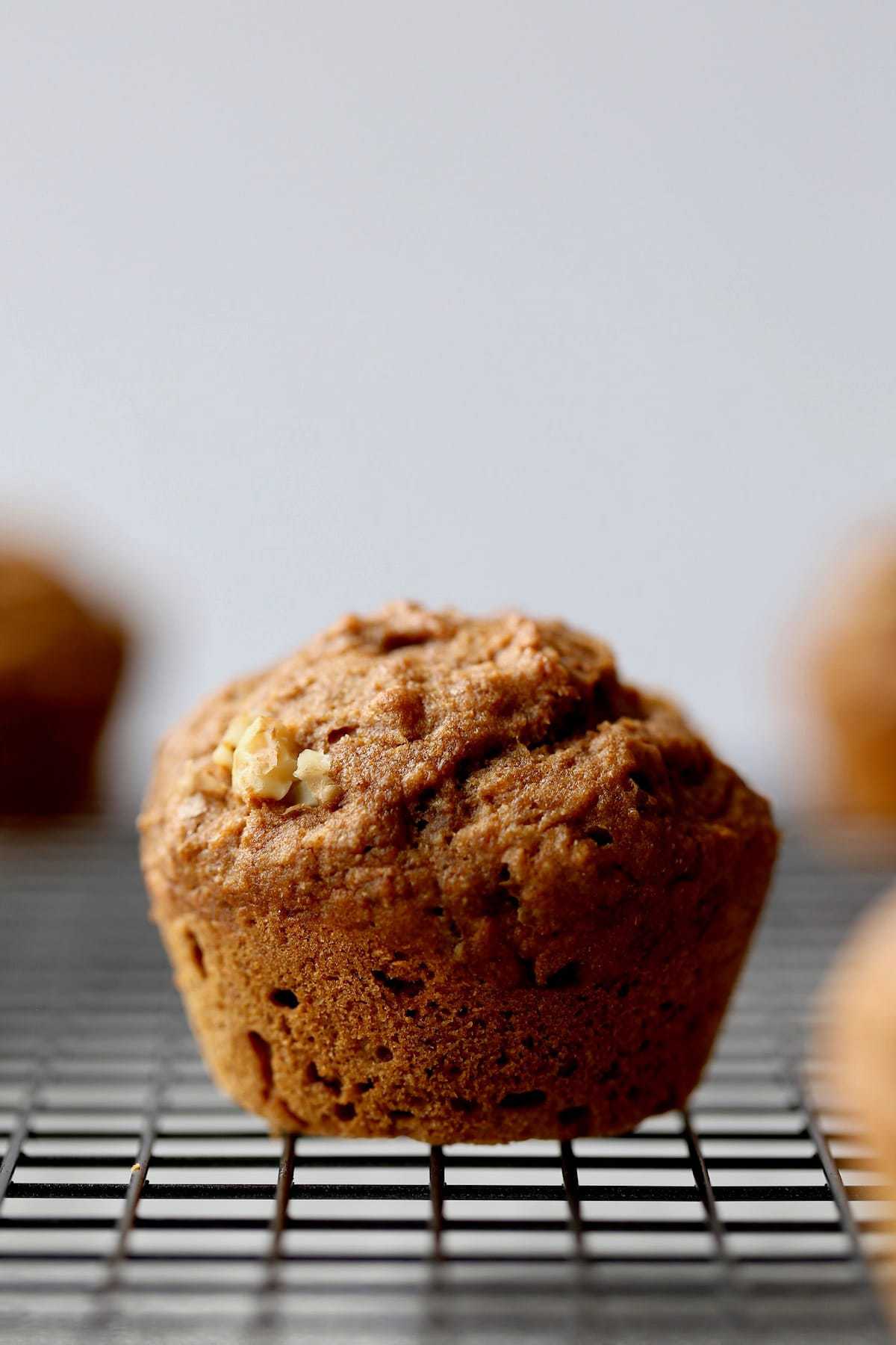 a vegan banana nut muffin cooling on a wire rack