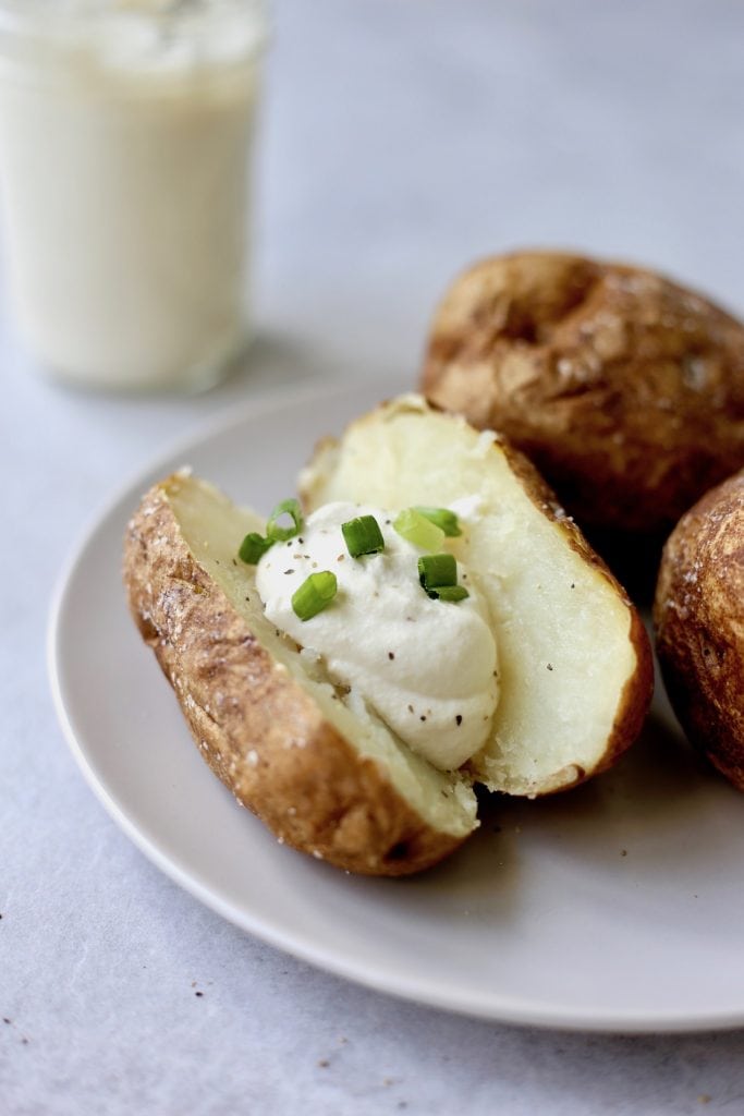 a baked potato stuffed with vegan cashew sour cream and green onions