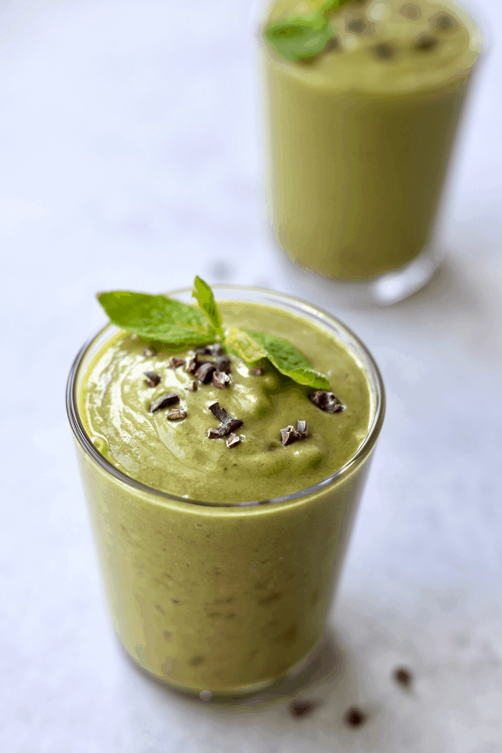 Cacao nibs and fresh mint garnishing a healthy green shamrock shake