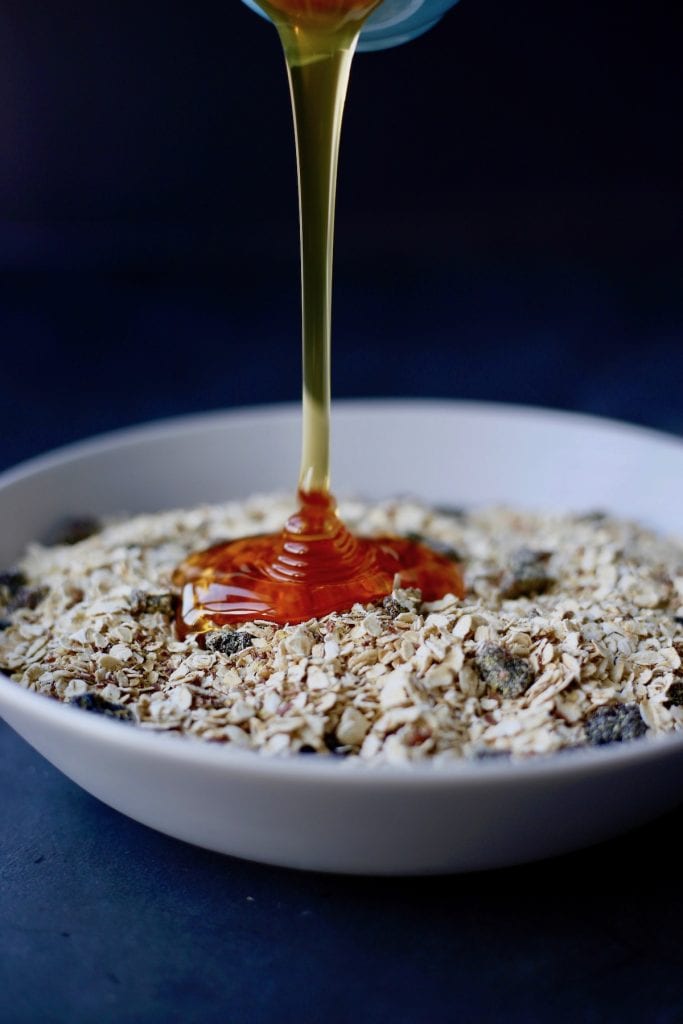 Honey being poured into a bowl of oatmeal and ground flaxseed
