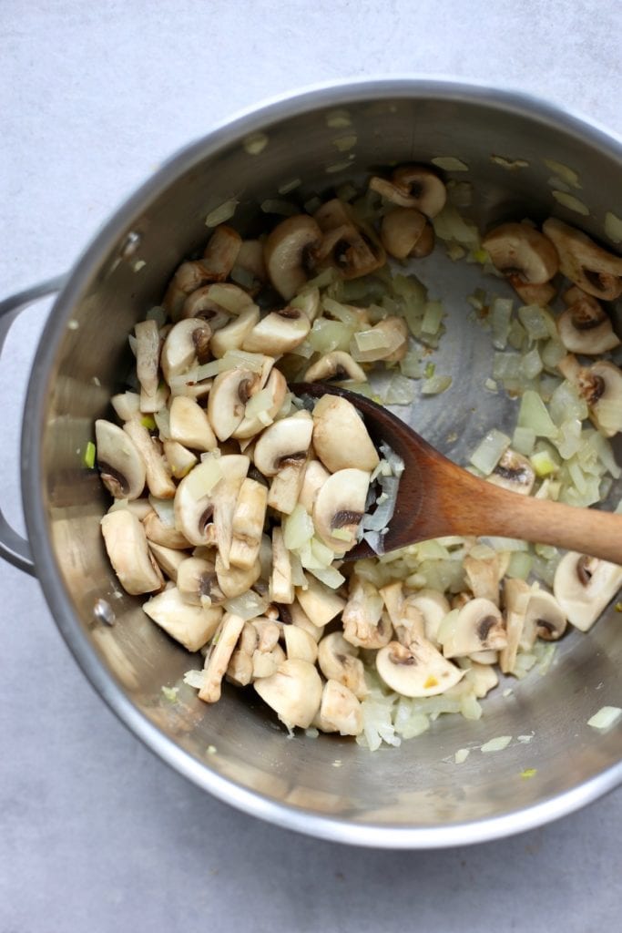 Mushrooms and onions sautéing in a saucepan