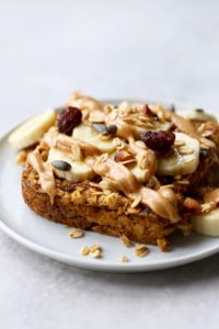 vegan baked oatmeal topped with peanut butter, bananas and raisins