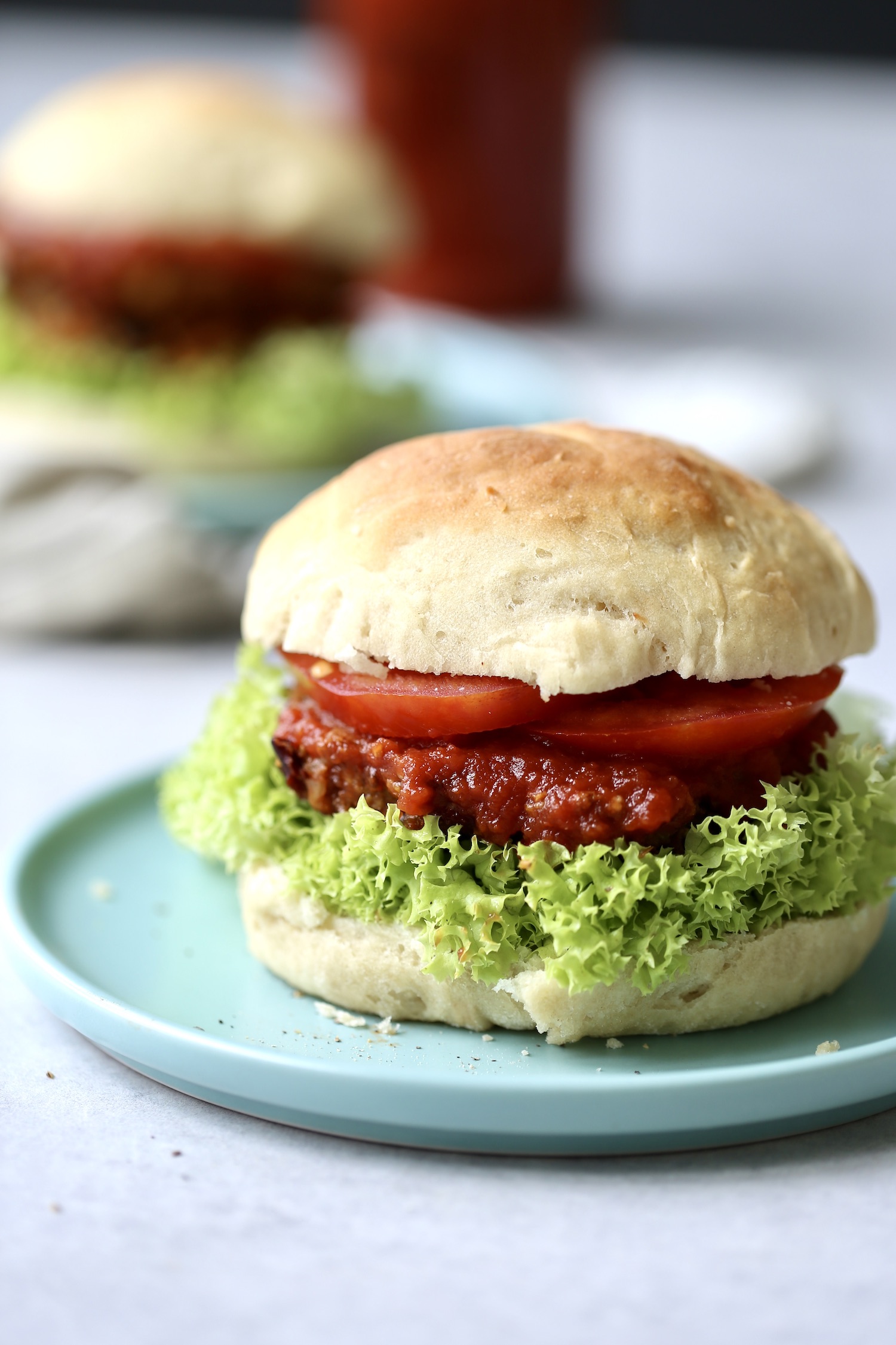 a homemade vegan burger bun filled with a veggie burger, lettuce, tomato and BBQ sauce
