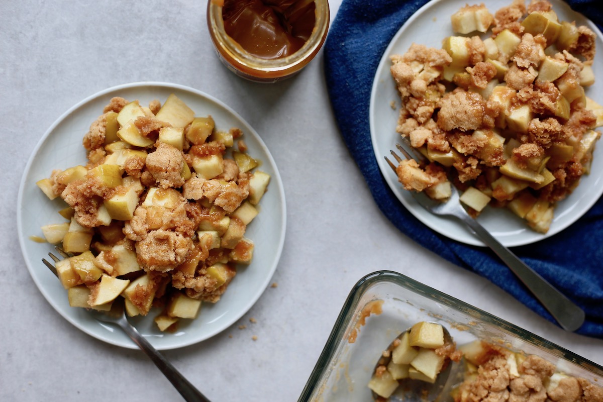 two plates of apple dump cake drizzled with caramel sauce