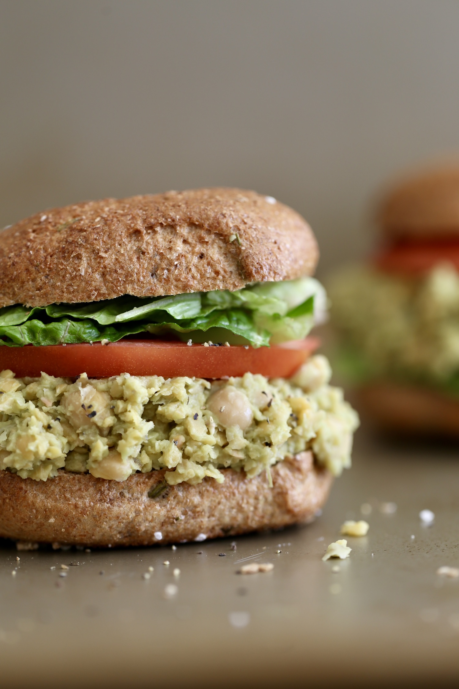 Avocado chickpea salad piled high on a toasted bagel with tomato