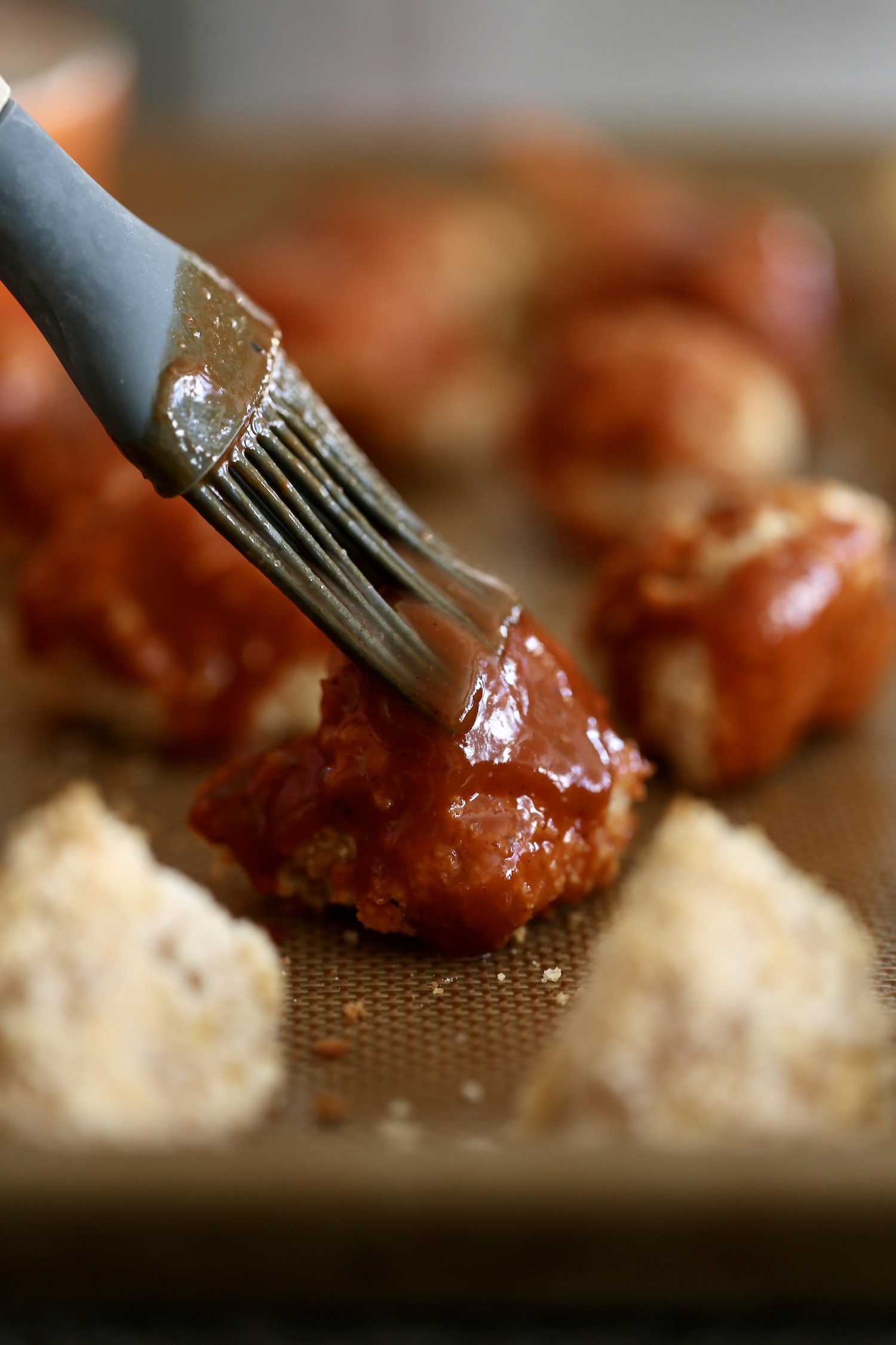 bbq sauce being slathered on a baked cauliflower wing