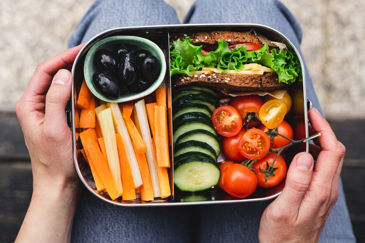 bento box with sandwich, cherry tomatoes, sliced cucumber, and carrot sticks