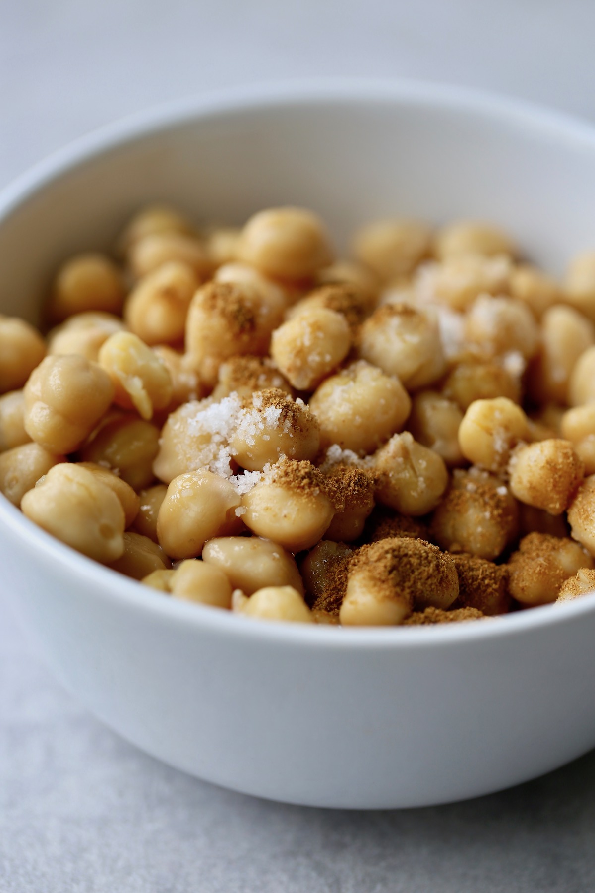 chickpeas in a bowl being coated with salt and spices