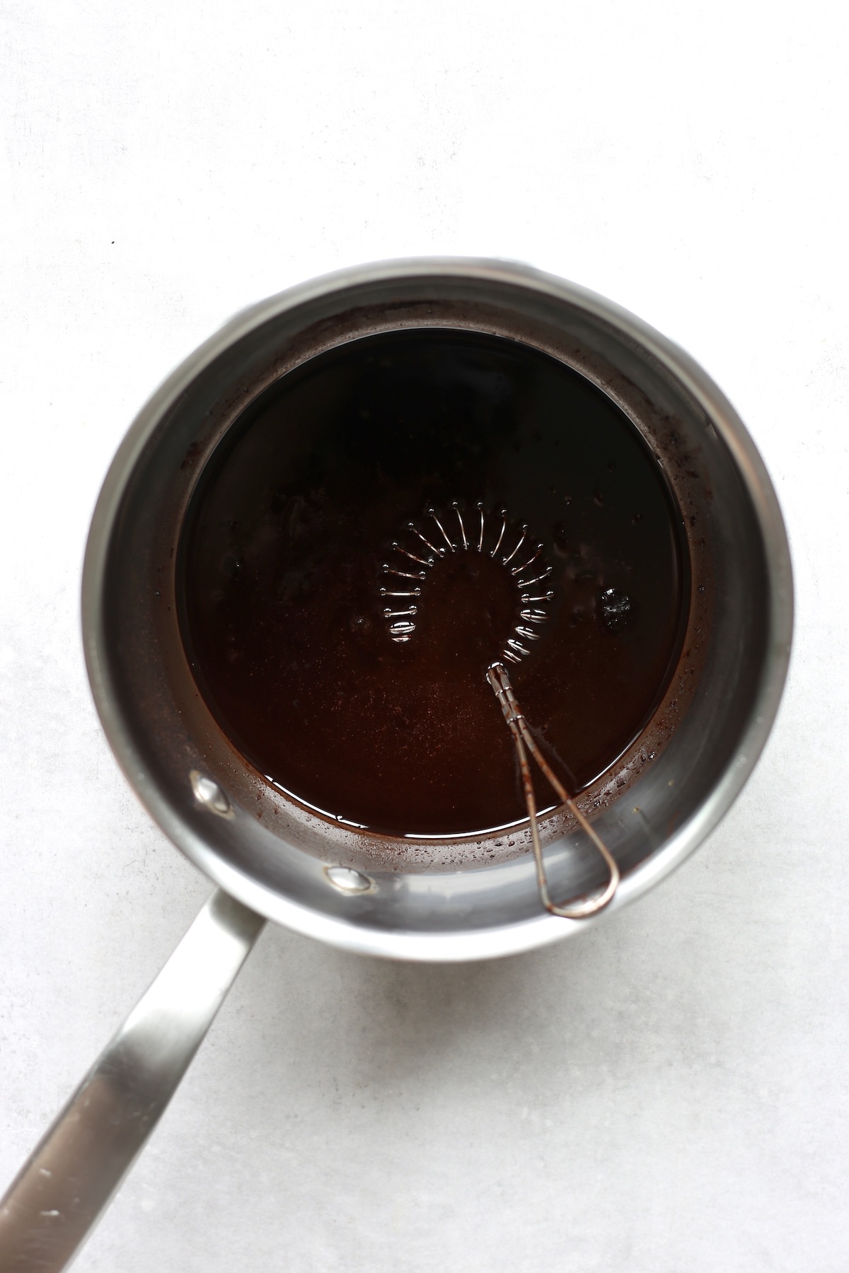 Coconut powder, coconut oil and maple syrup melted together in a saucepan in a whisk. 
