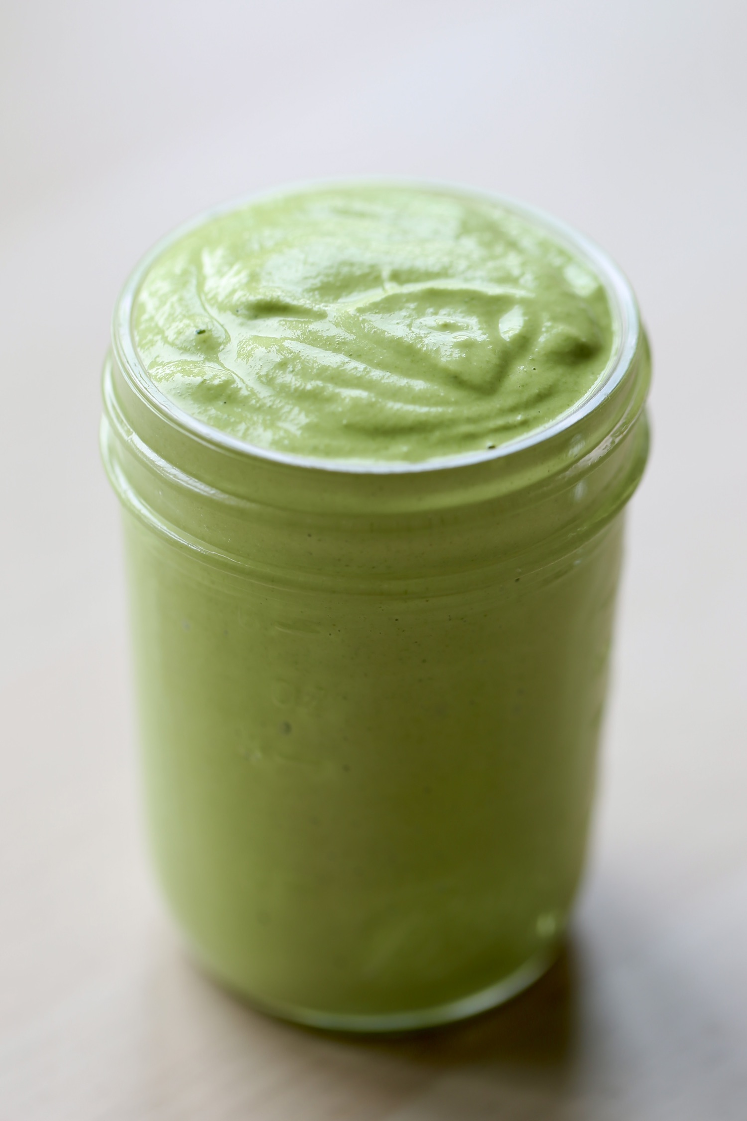 A mason jar full of vibrant green cilantro lime sauce. 