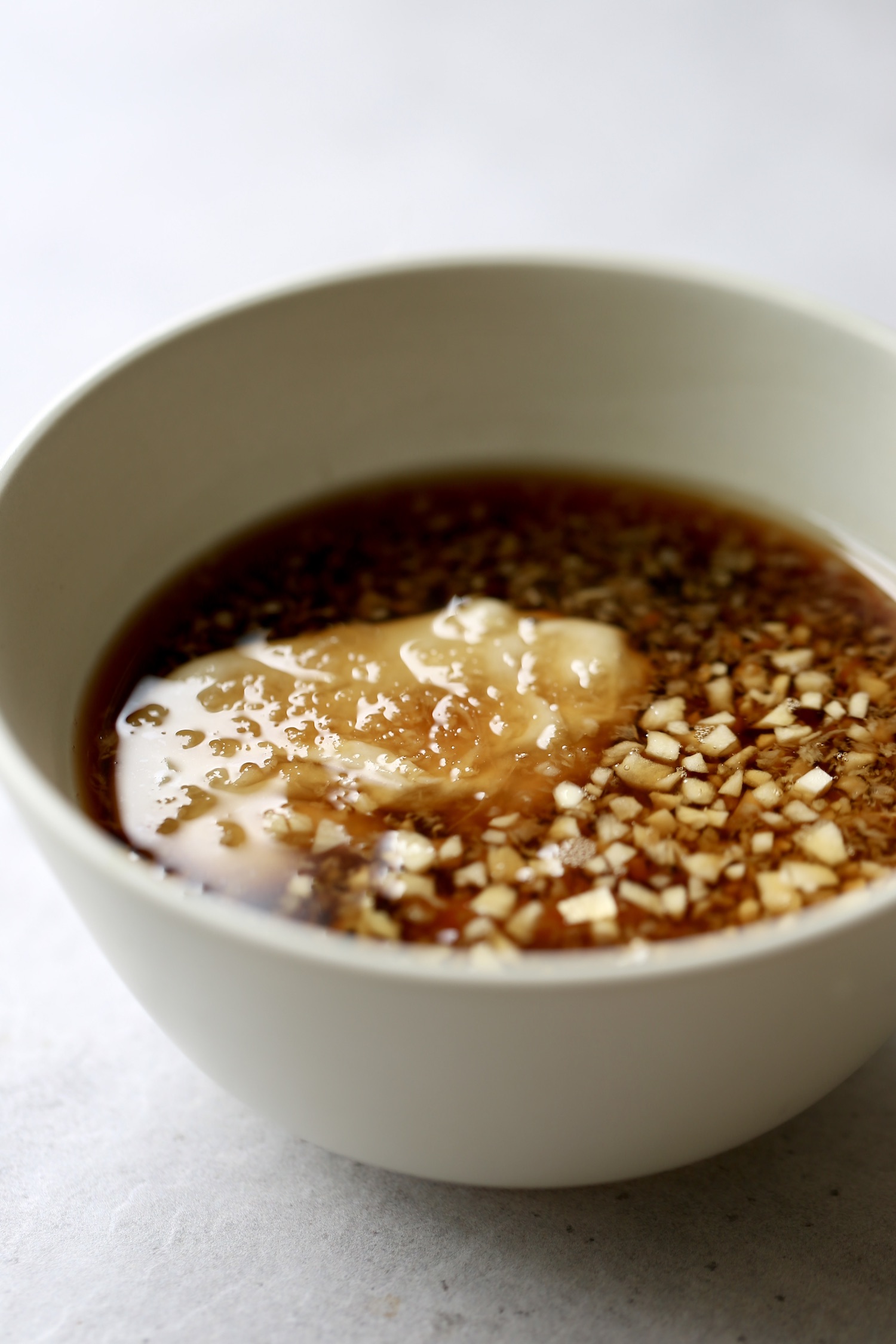 Tahini, soy sauce, maple syrup, ginger and garlic in a small tan bowl. 