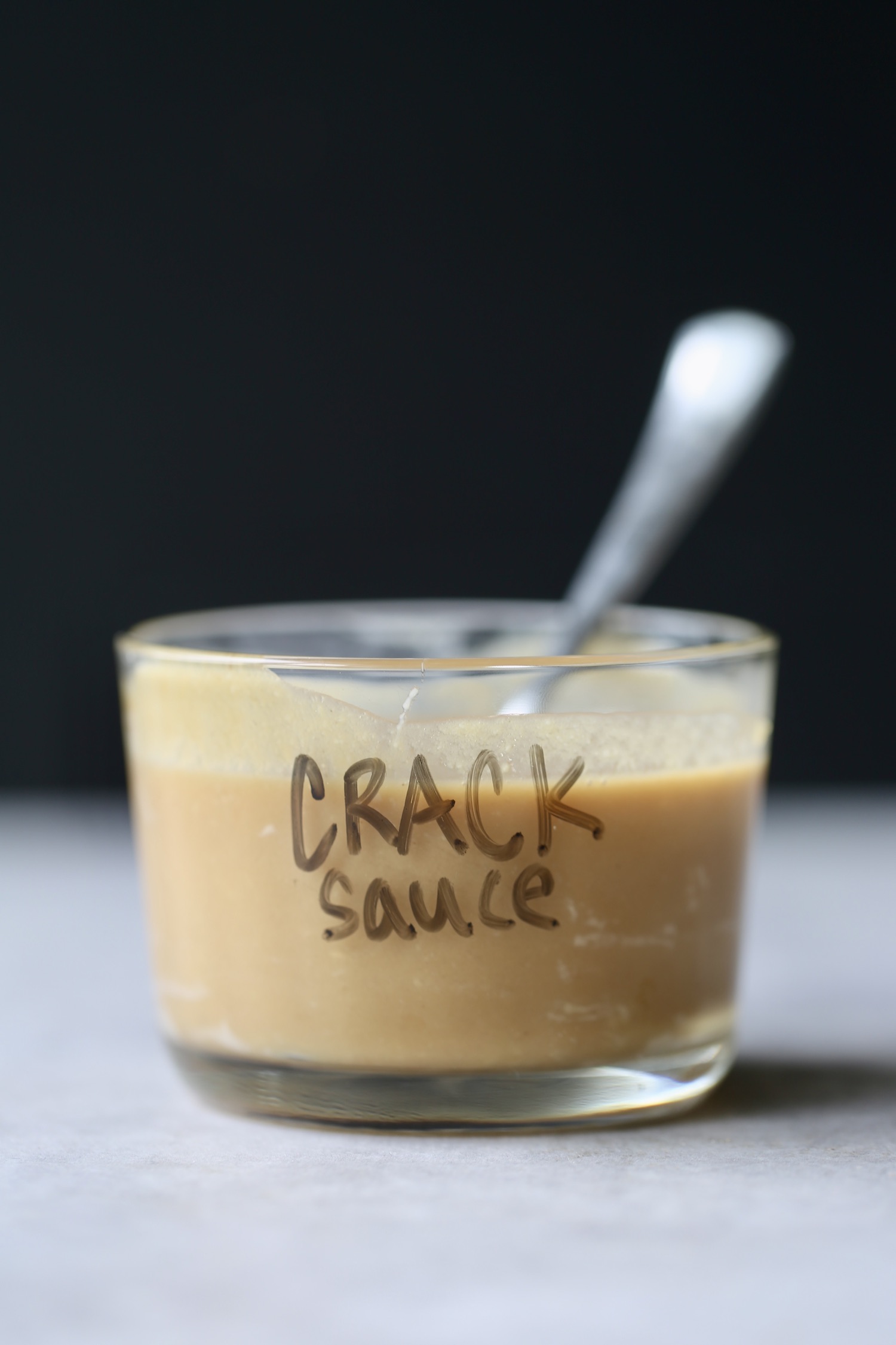 A glass bowl with "Crack Sauce" written on the front with white board marker. 