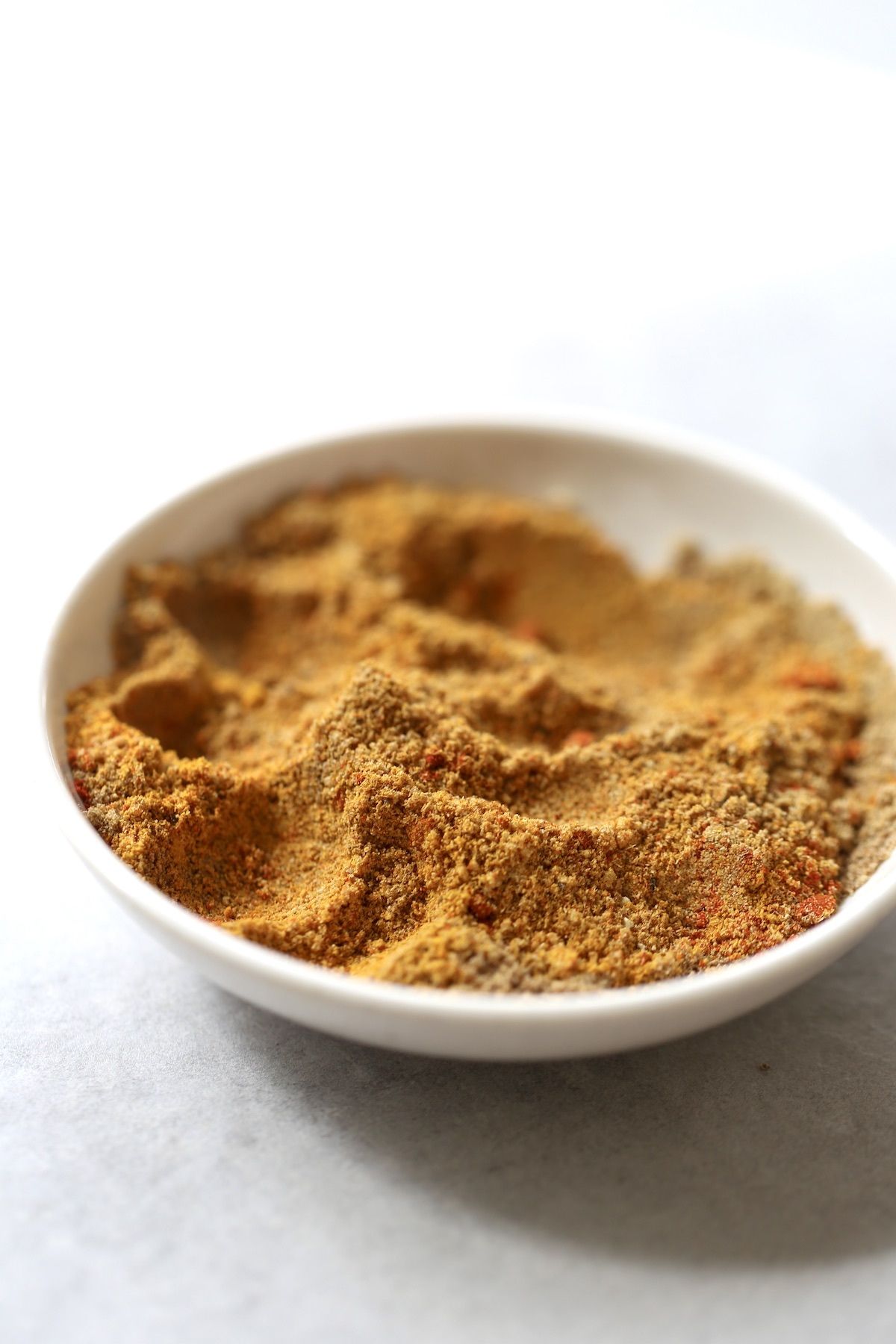 A blend of orange and brown spices in a small white bowl.