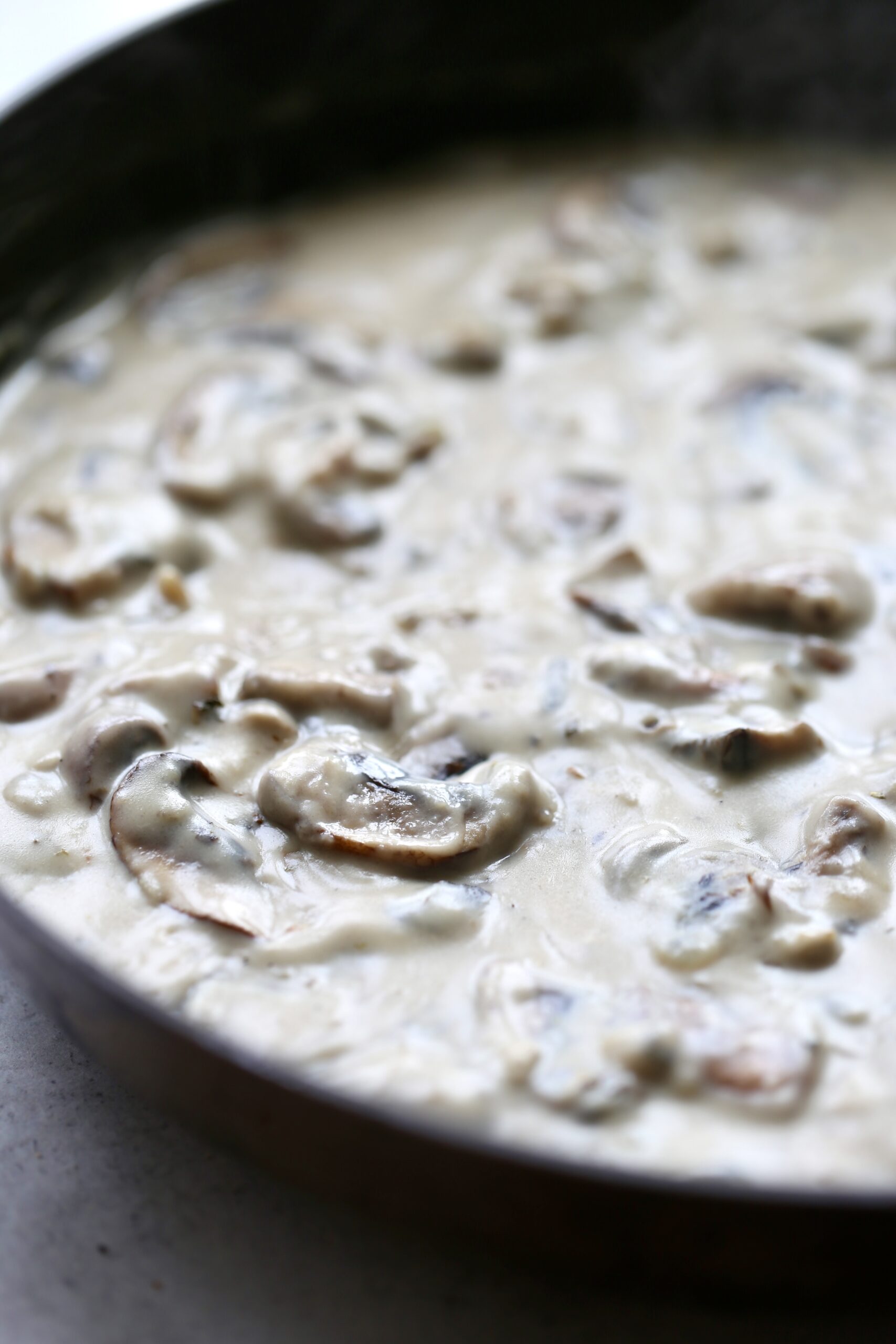 A close up shot of sliced mushrooms in a creamy dairy-free gravy. 