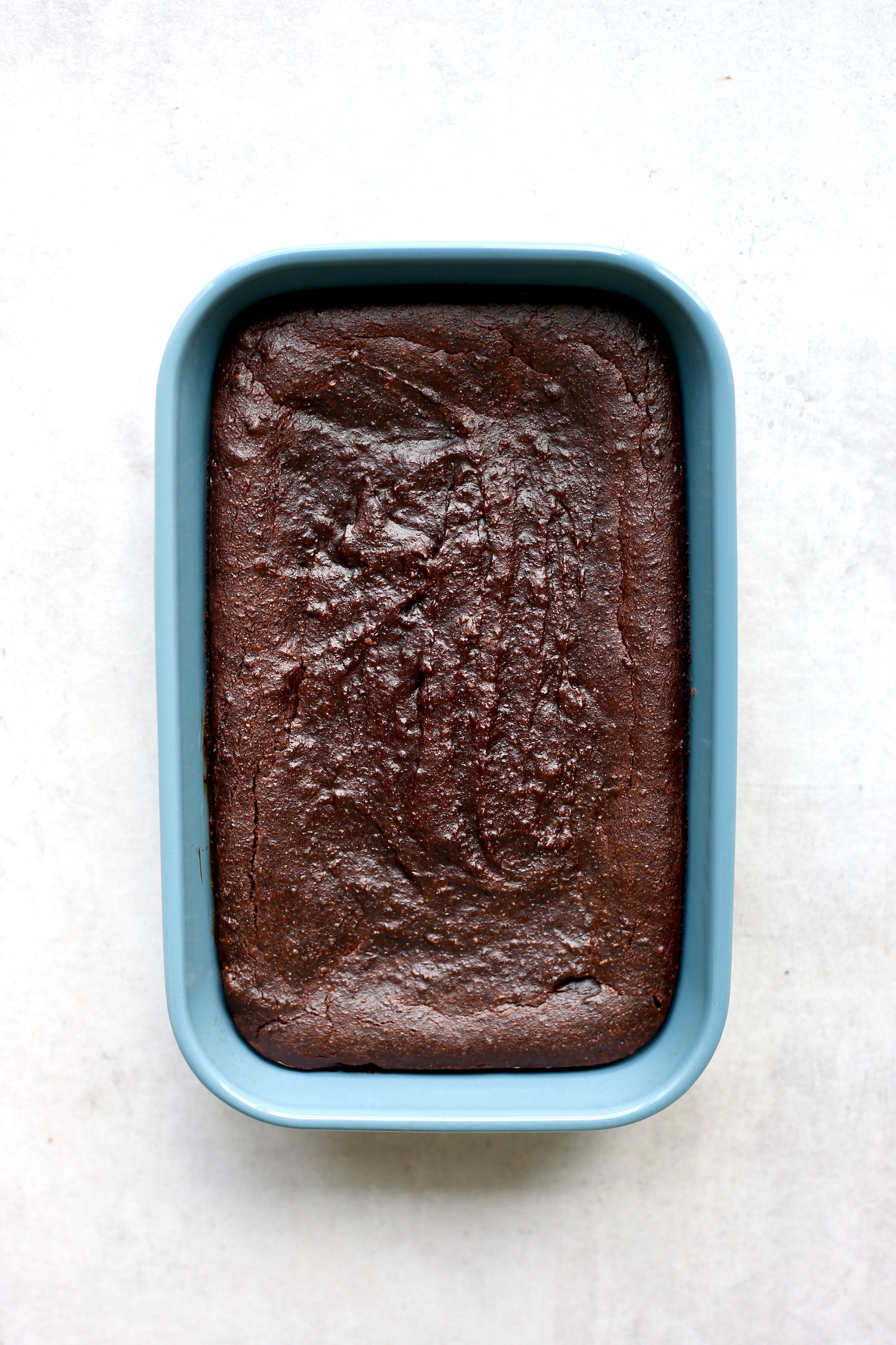 Date brownies in a blue baking dish right after baking. 