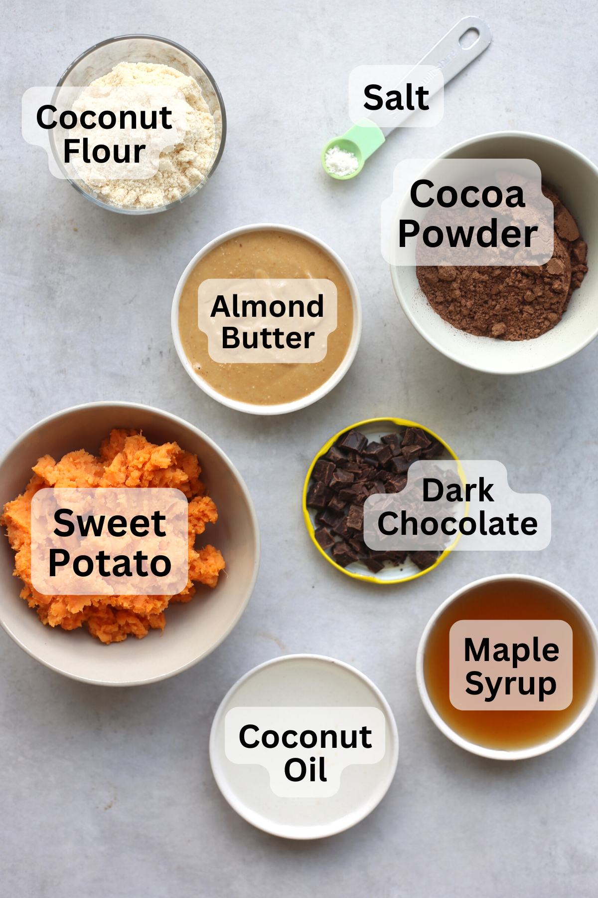 Coconut flour, cocoa powder, almond butter, mashed sweet potato and other ingredients measure out into small bowls.