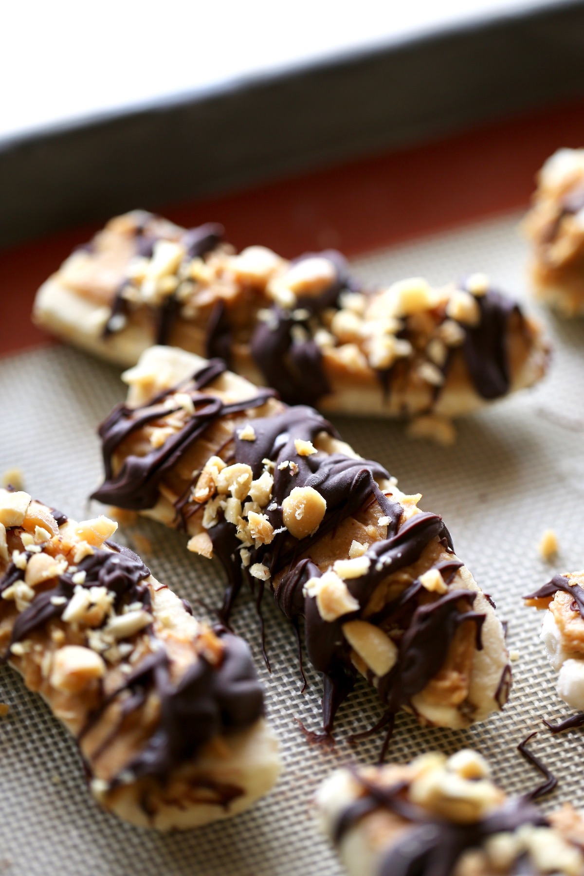 frozen bananas topped with peanut butter, chocolate and roasted peanuts