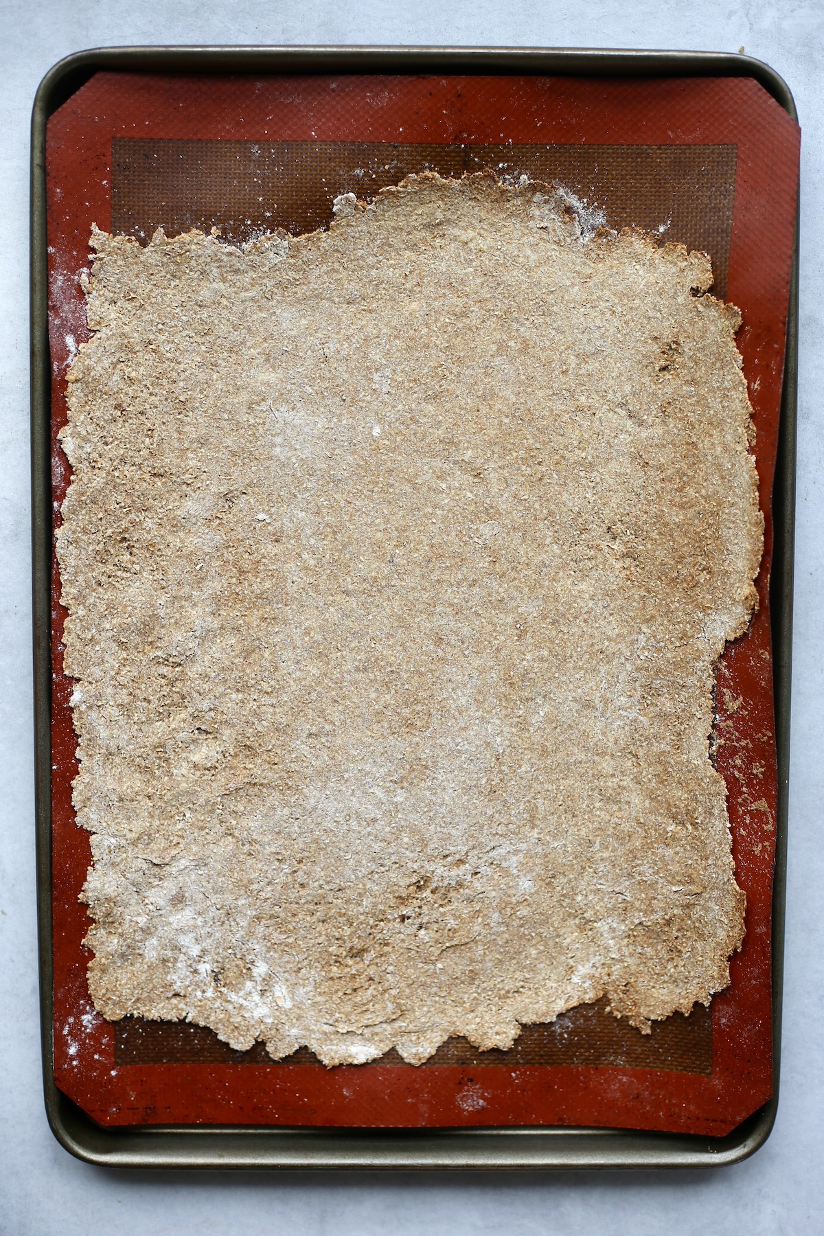 A thin and crispy sheet of bran flake cereal dough on a silicone baking mat.