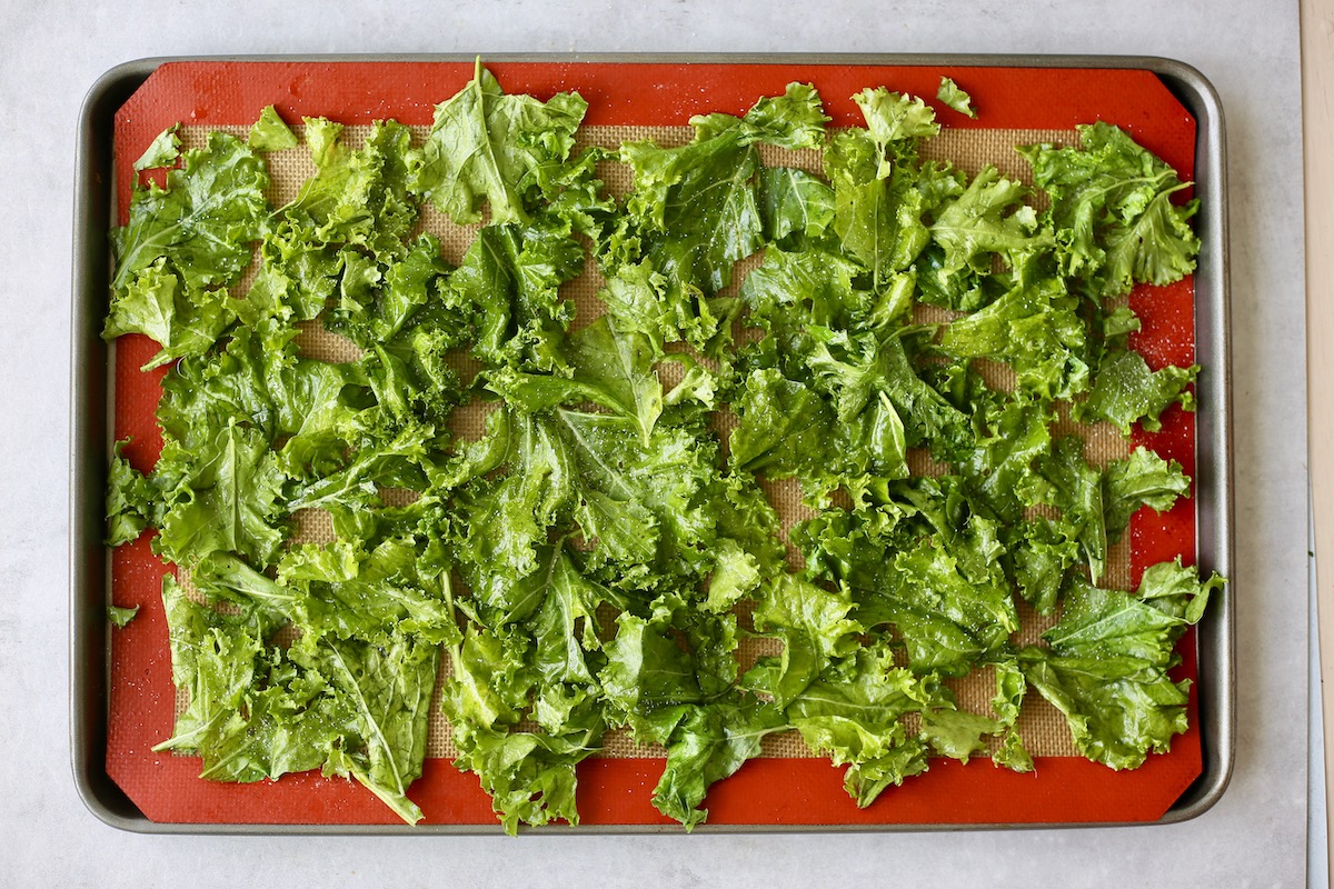 kale leaves coated in oil and salt on a baking sheet