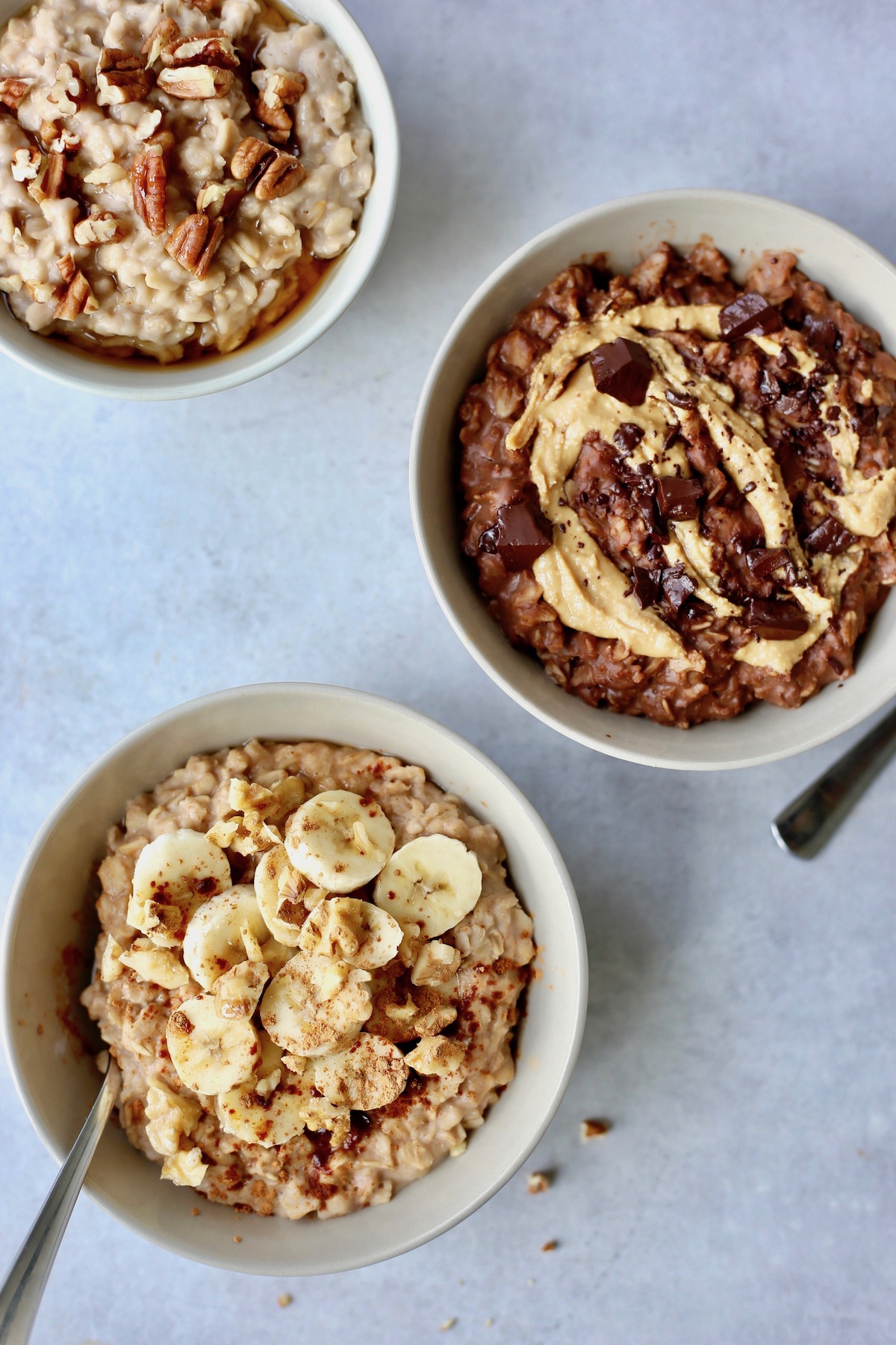 three bowls of oatmeal topped with a variety of toppings