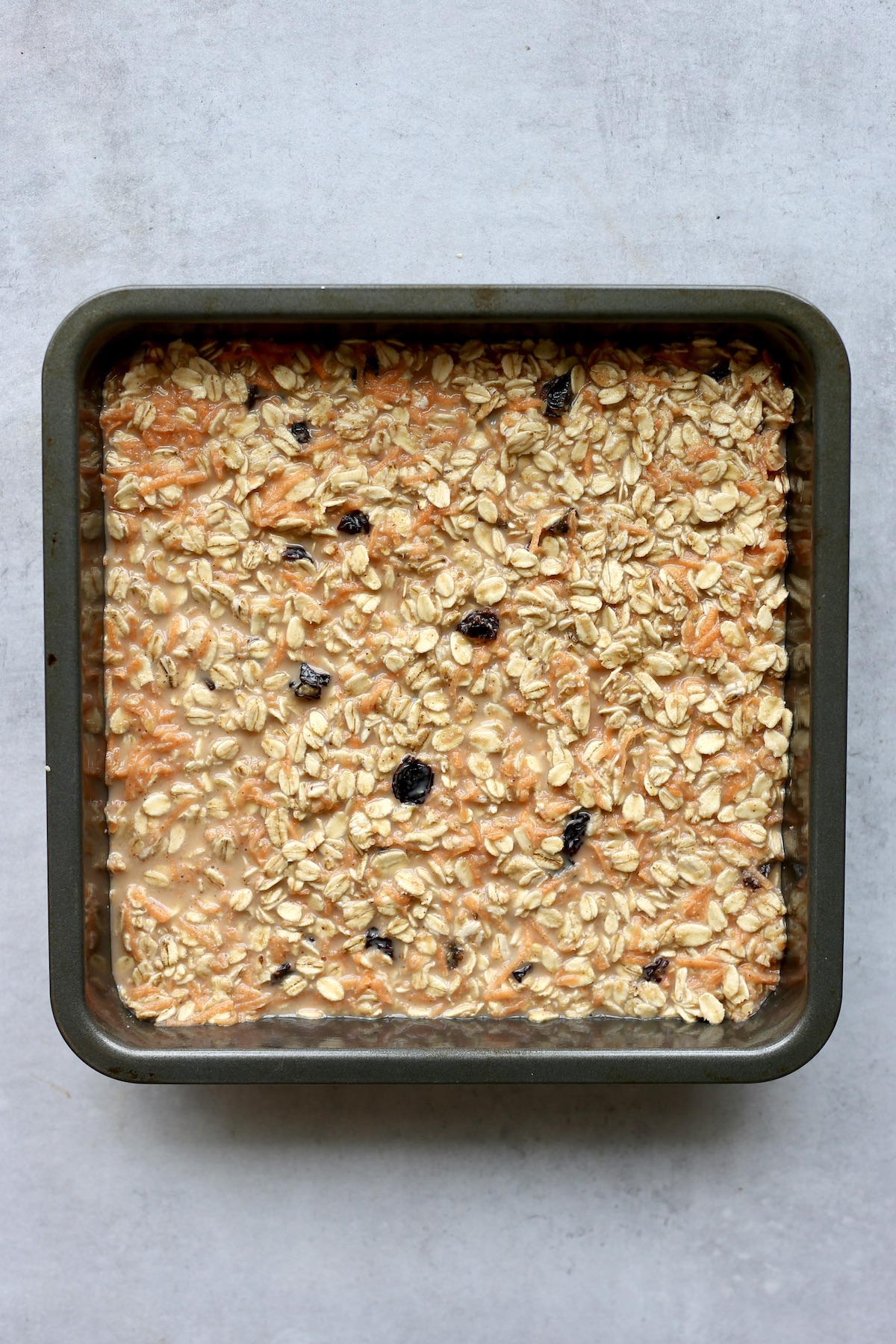 An overhead shot of make ahead carrot cake baked oatmeal in an 8x8 baking dish before it has baked. 