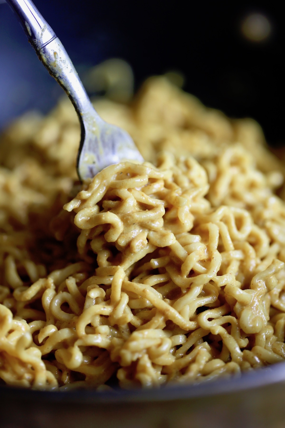 a fork scooping up some creamy vegan curry ramen noodles