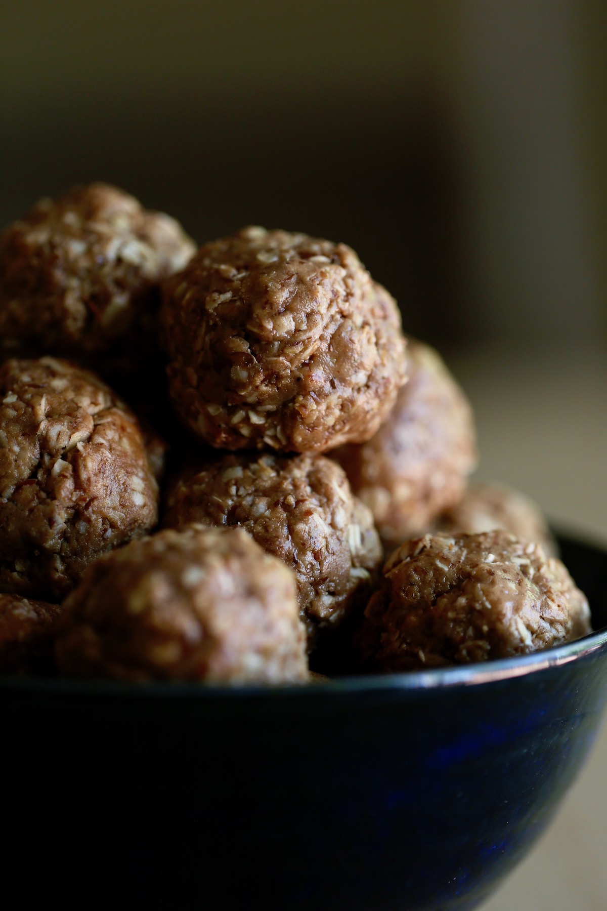 Golden brown peanut butter protein balls in a blue bowl.