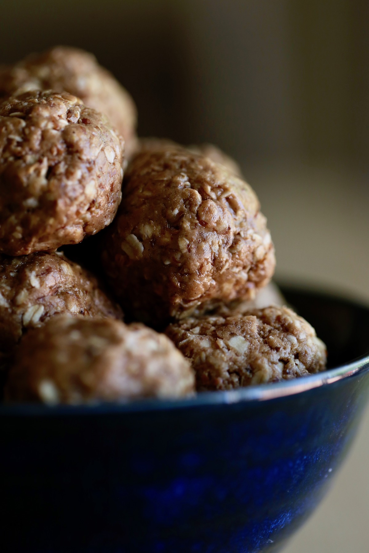A close up of peanut butter protein balls piled high in a bowl bowl. 