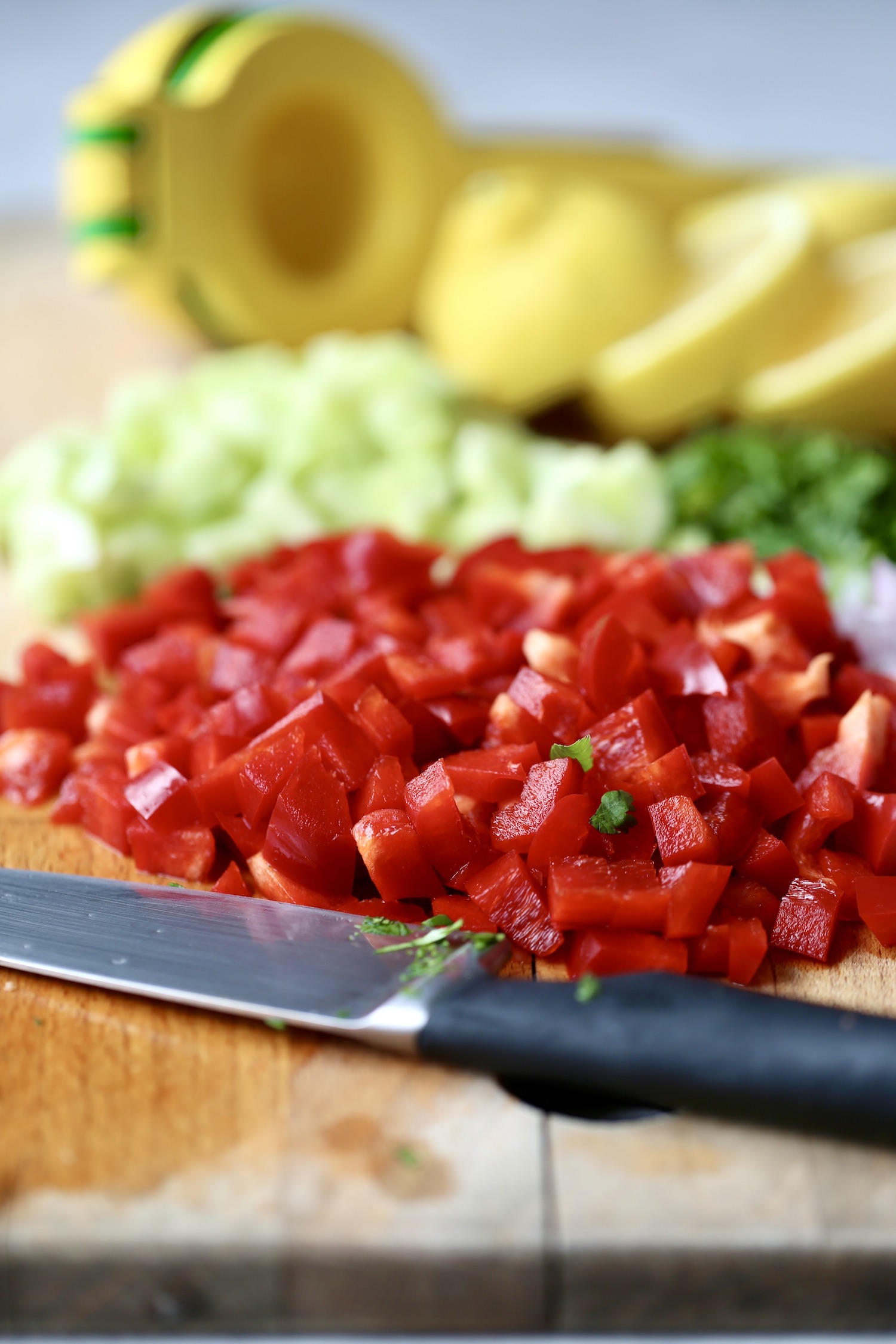 red bell pepper and cucumber chopped up on a cutting board for couscous salad