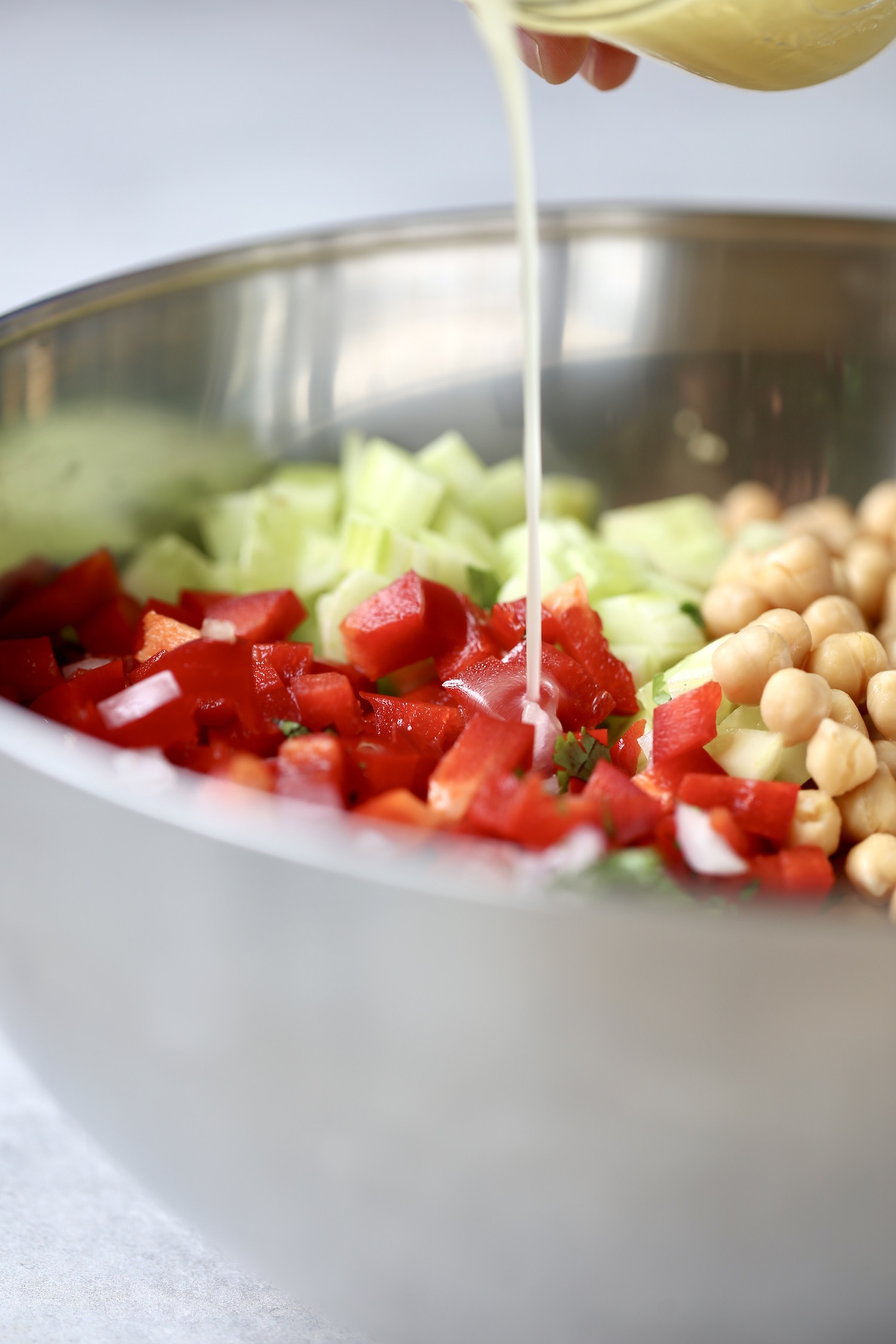 lemon vinaigrette being poured over chopped veggies for lemon couscous salad