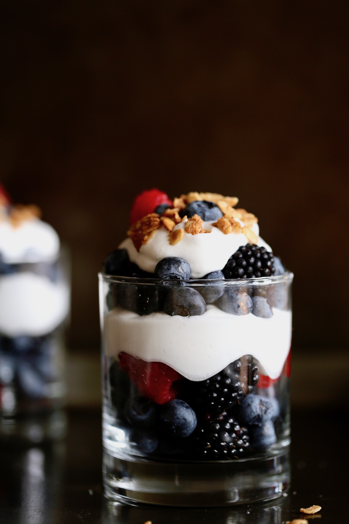 berries layered with whipped cream and granola to create simple vegan berries and cream parfaits