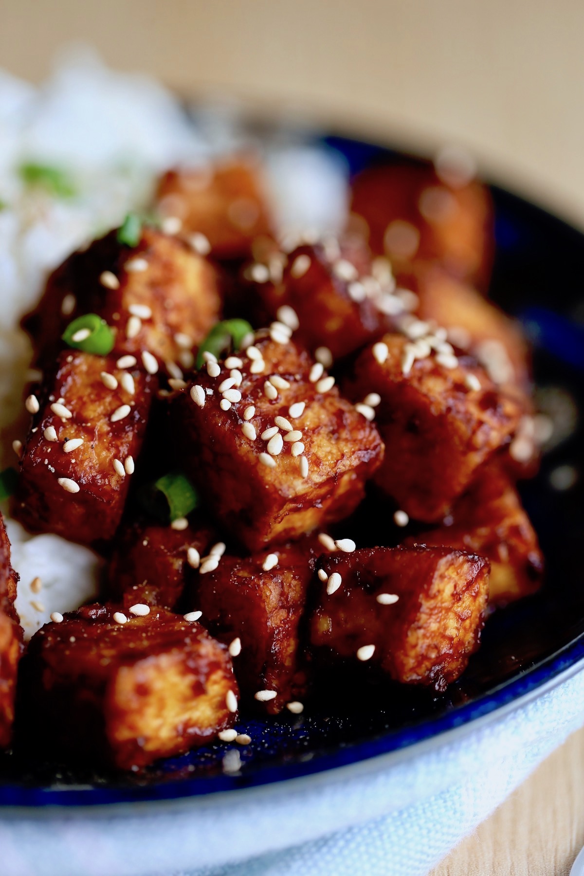 Sweet and sour tofu served with coconut rice and garnished with green onion and sesame seeds
