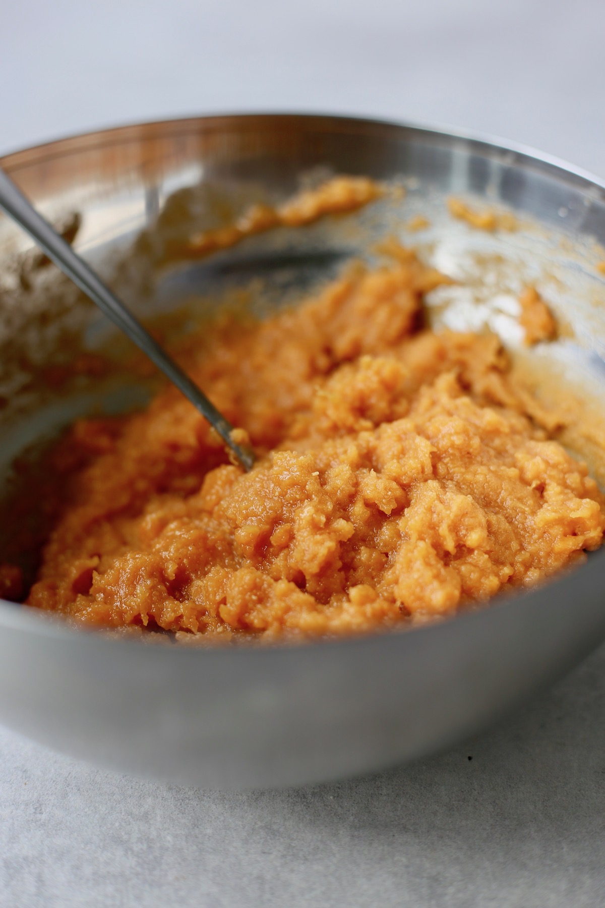 A large bowl of bright orange, mashed sweet potato.