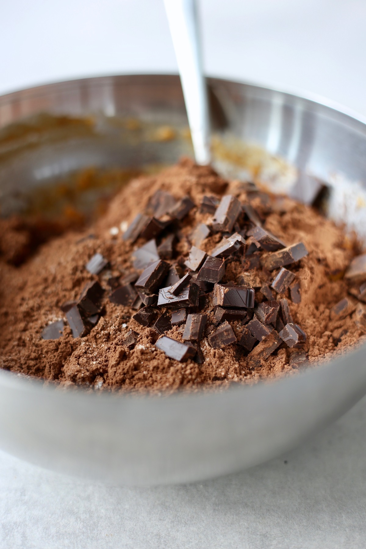 Cocoa powder and chunks of chocolate in a large mixing bowl.