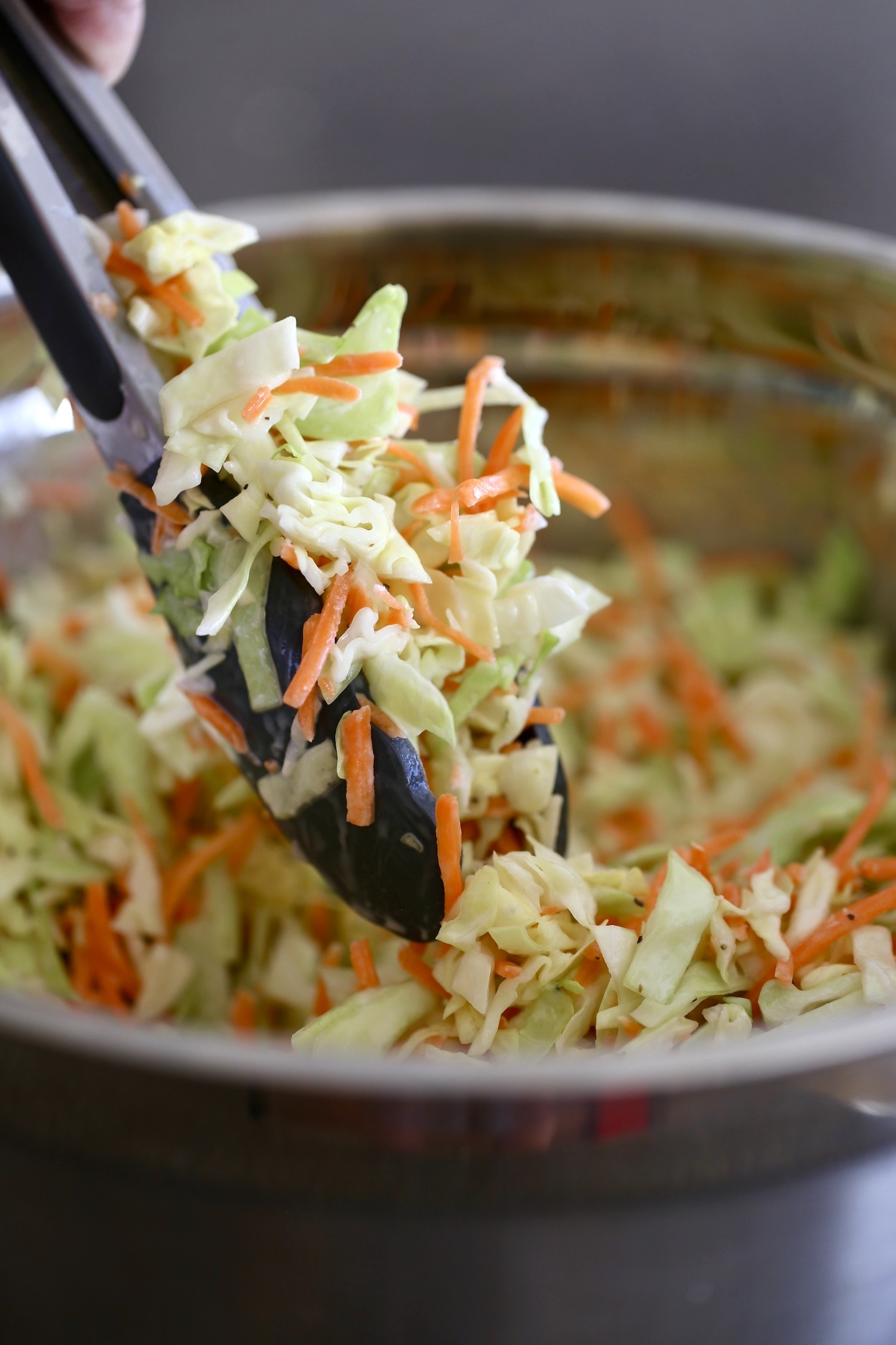 creamy vegan coleslaw being scooped up with tongs