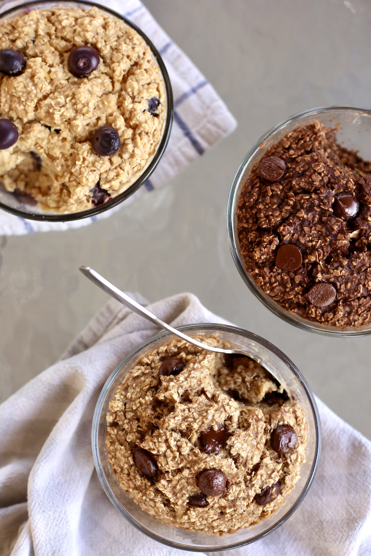 An overhead shot of three flavors of vegan baked oats in glass single-serve baking dishes.