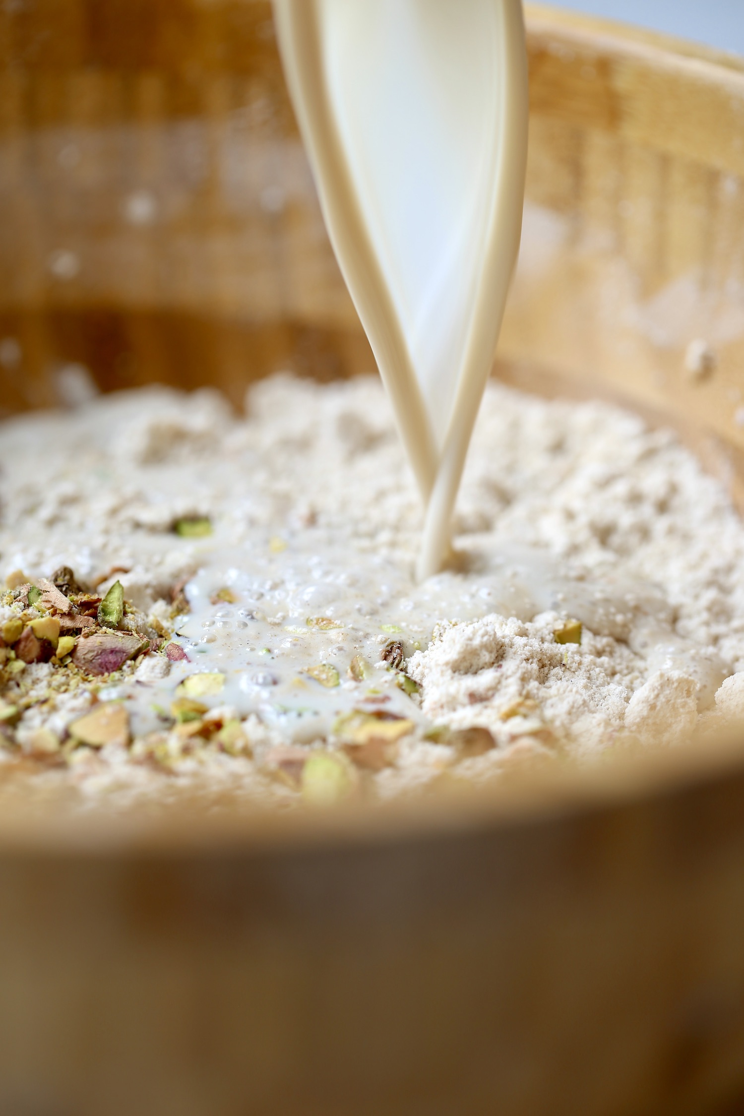 Milk being added to a bowl of flour for vegan scones