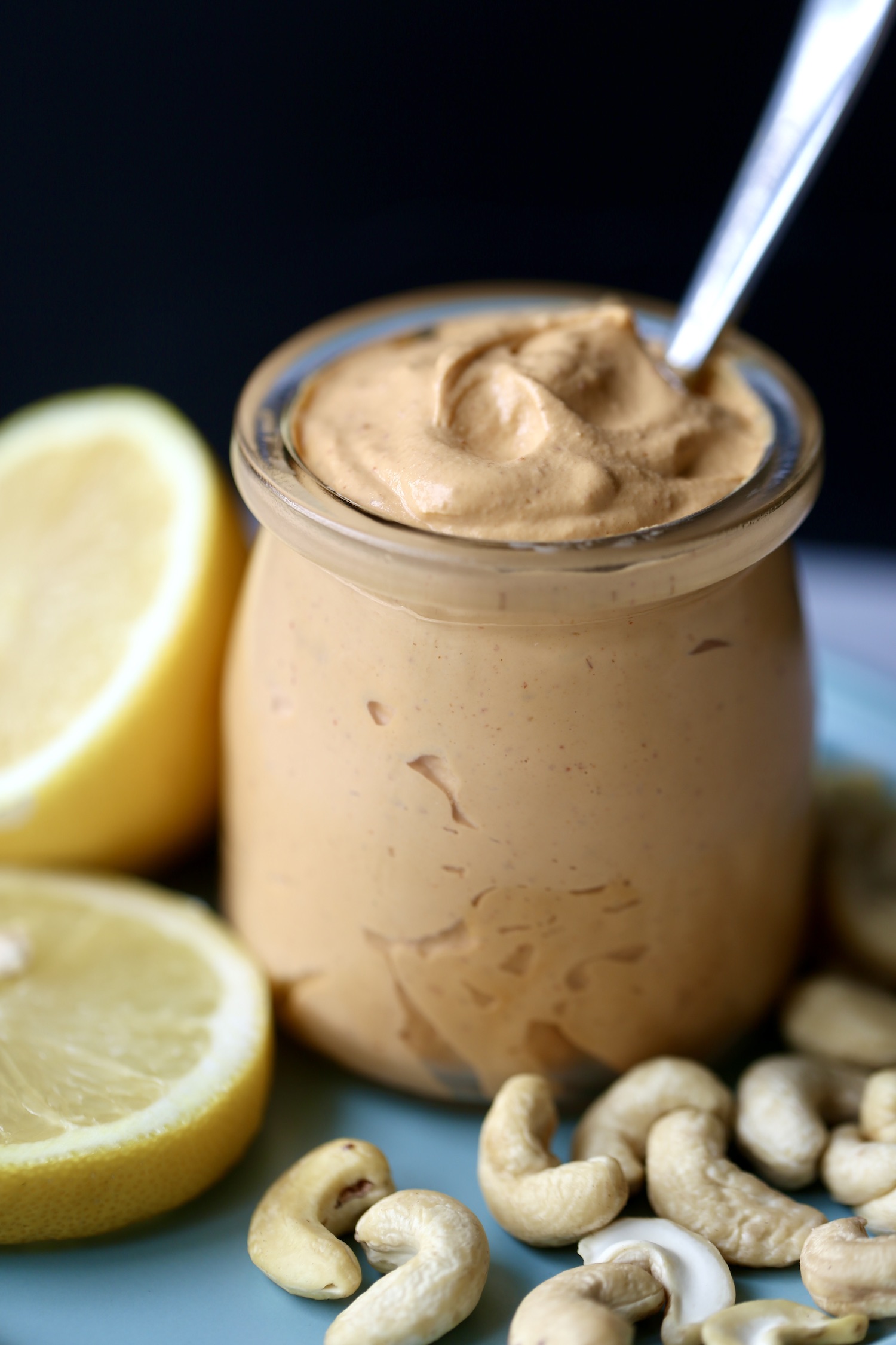 Thick and creamy vegan chipotle mayo in a small glass jar with a spoon sticking out of it. 