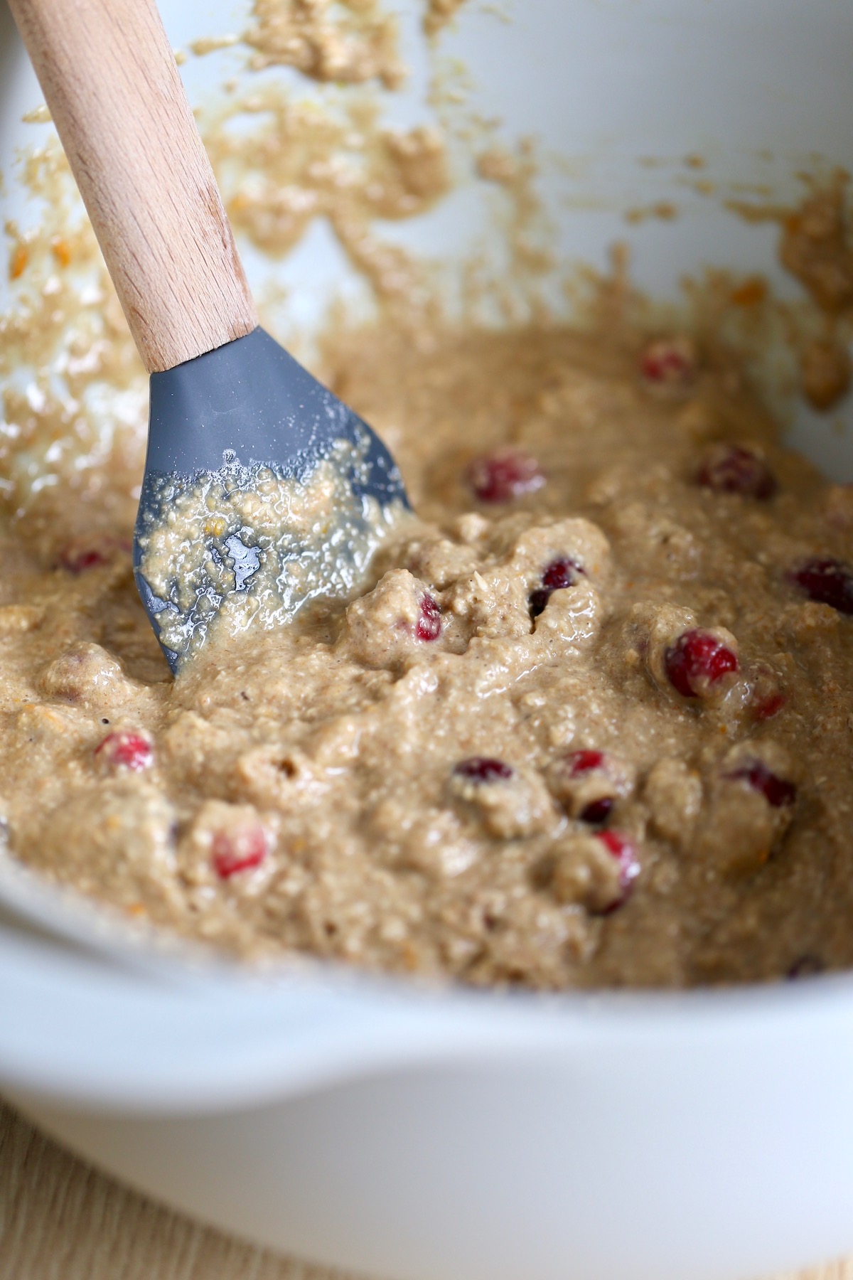 cranberry orange muffin batter being stirred with a spatula
