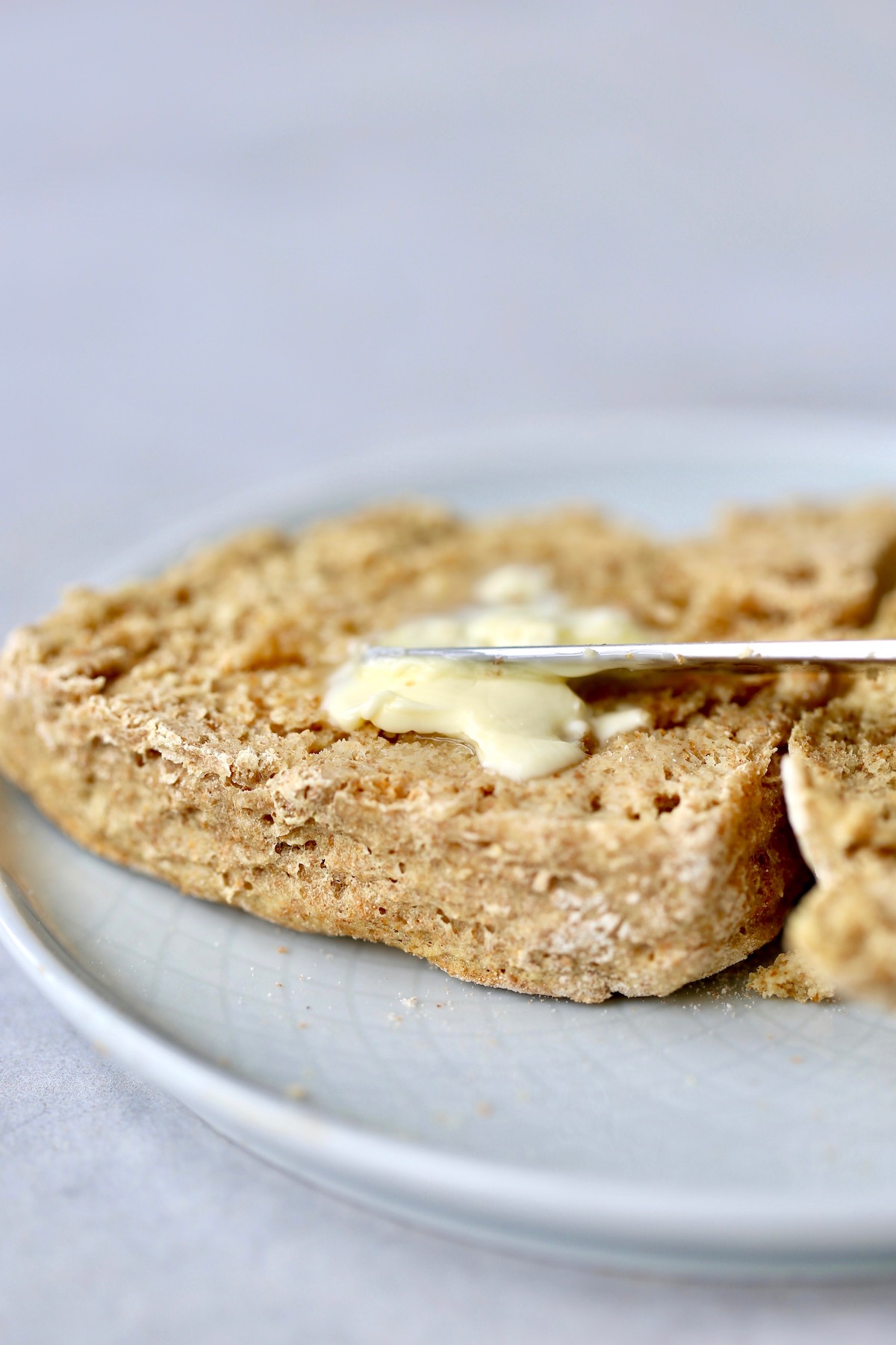 vegan irish soda bread cut in half being smeared with butter