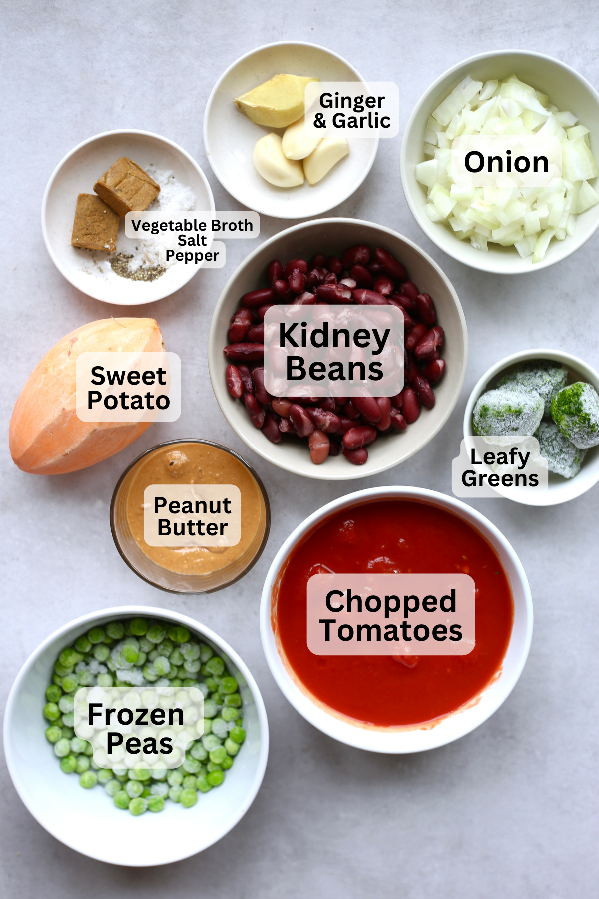 An overhead shot of the ingredients for vegan maafe measured out into bowls with labels overtop.