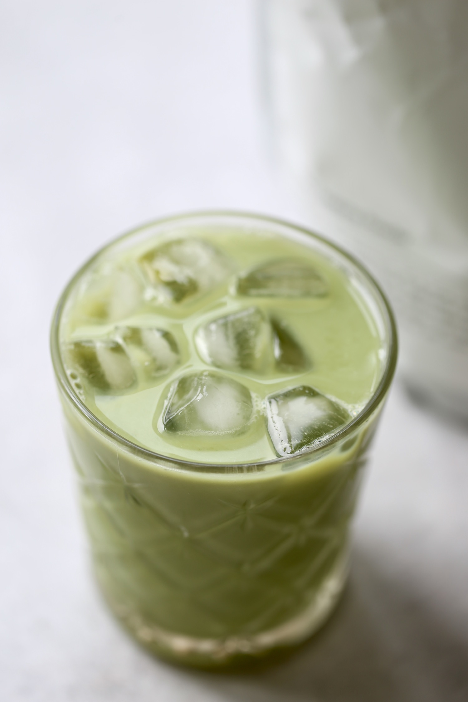 Ice cubes poking out of a glass of dairy-free matcha latte. 