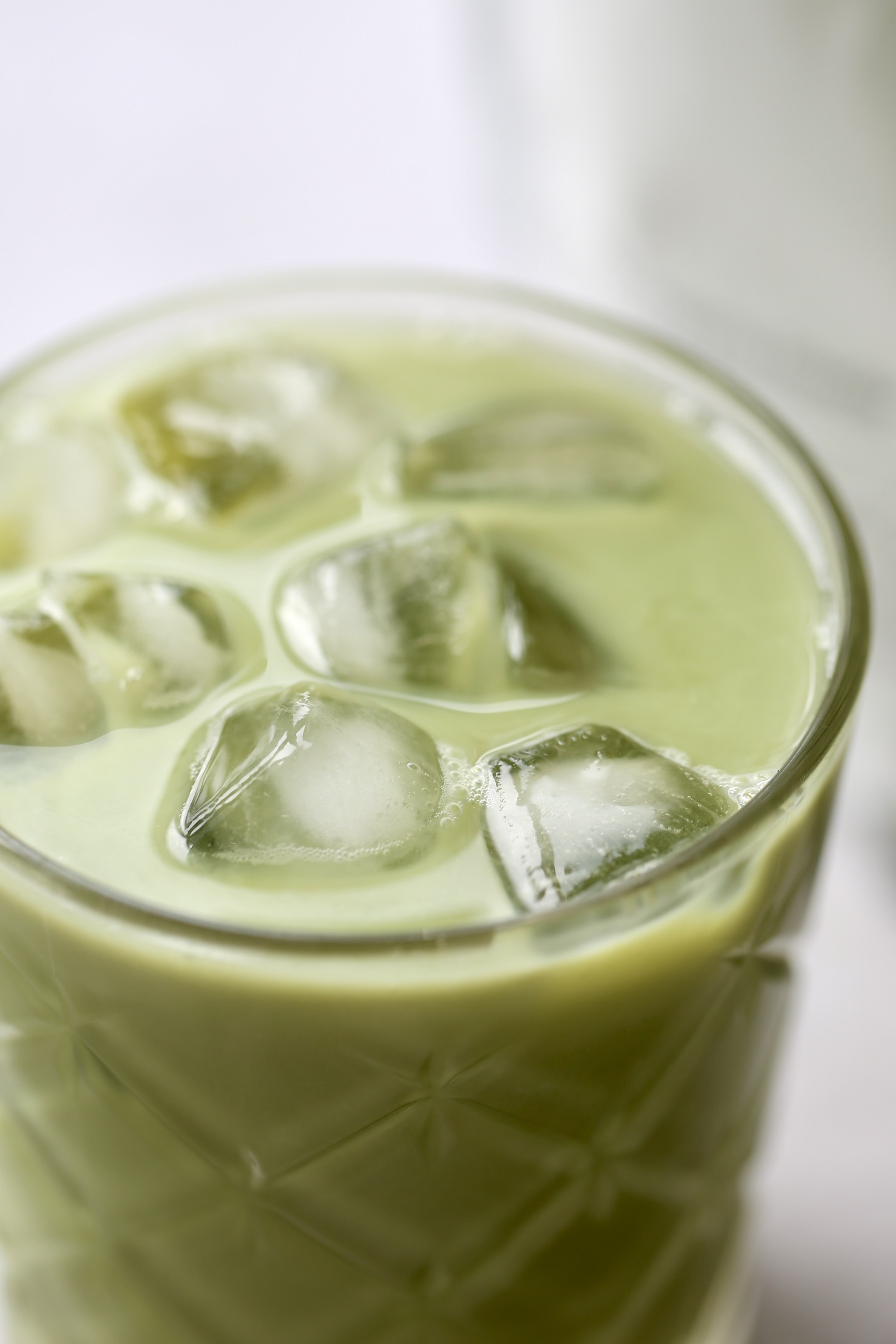 A close up of a vegan iced matcha latte in a glass. 