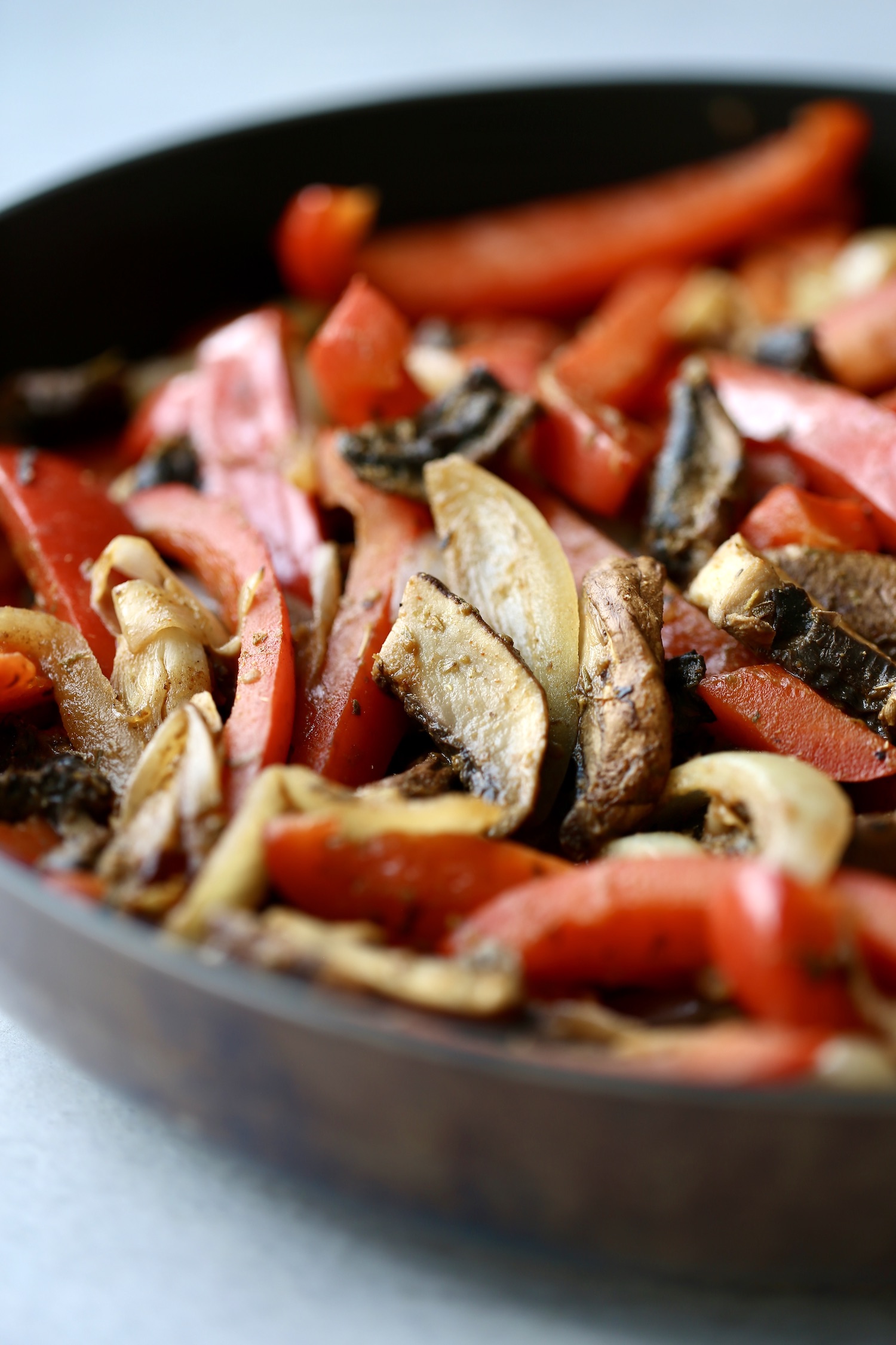 sauteed red bell peppers, mushrooms and onions in a skillet for vegan fajitas