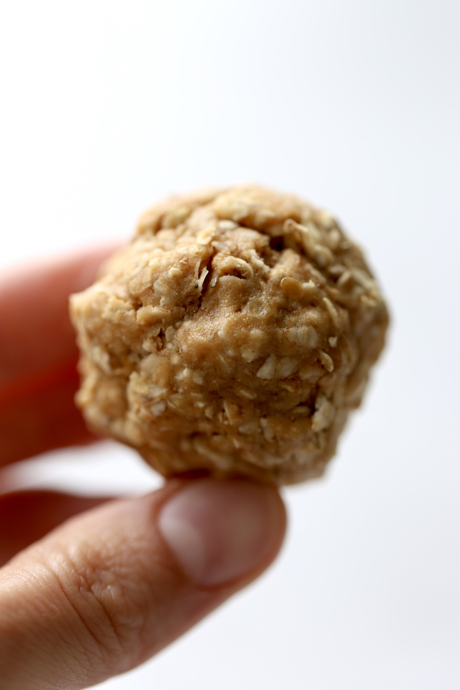 A hand holding up a peanut butter protein ball. 