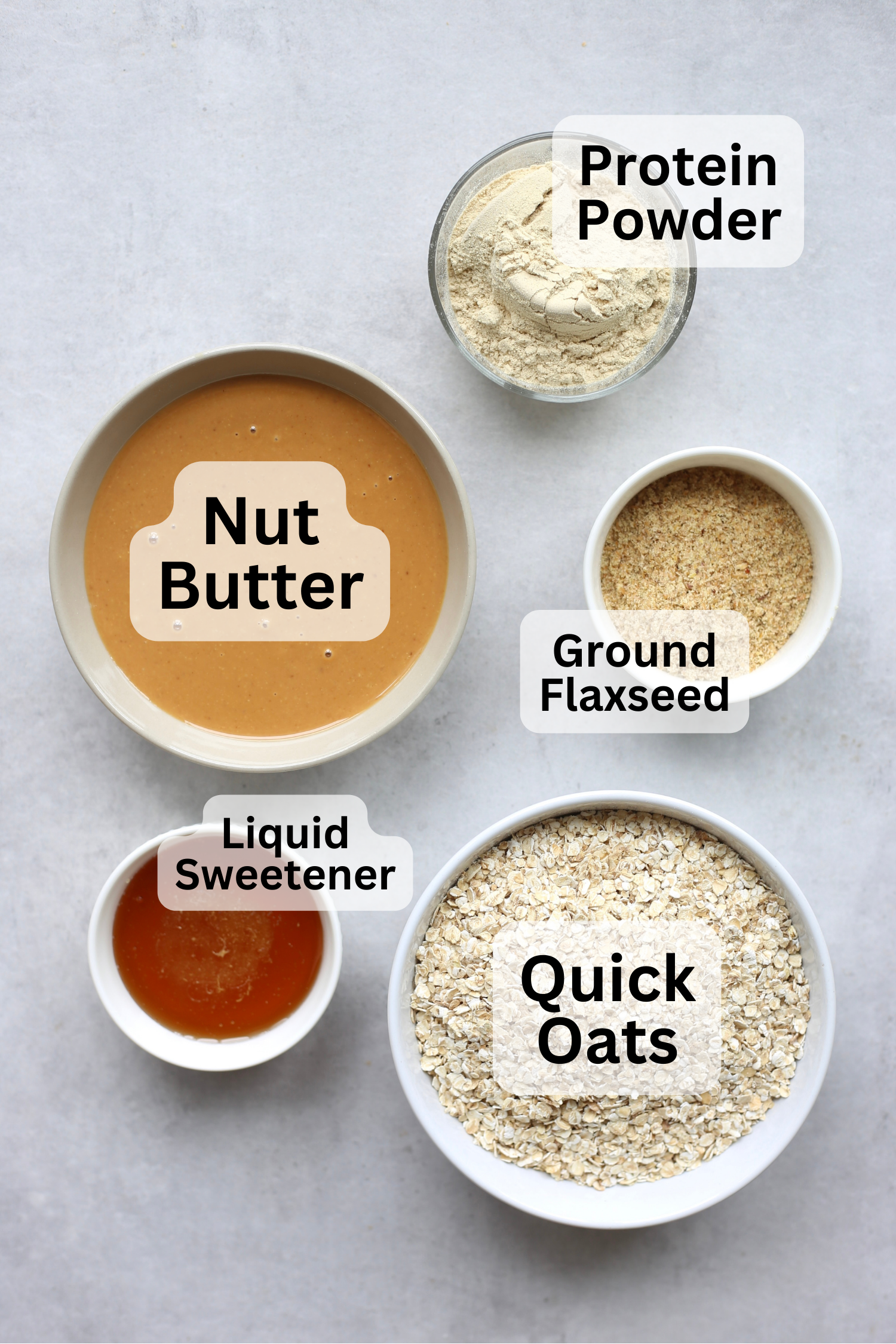 All of the ingredients for vegan protein balls measured out into bowls with labels over top. 