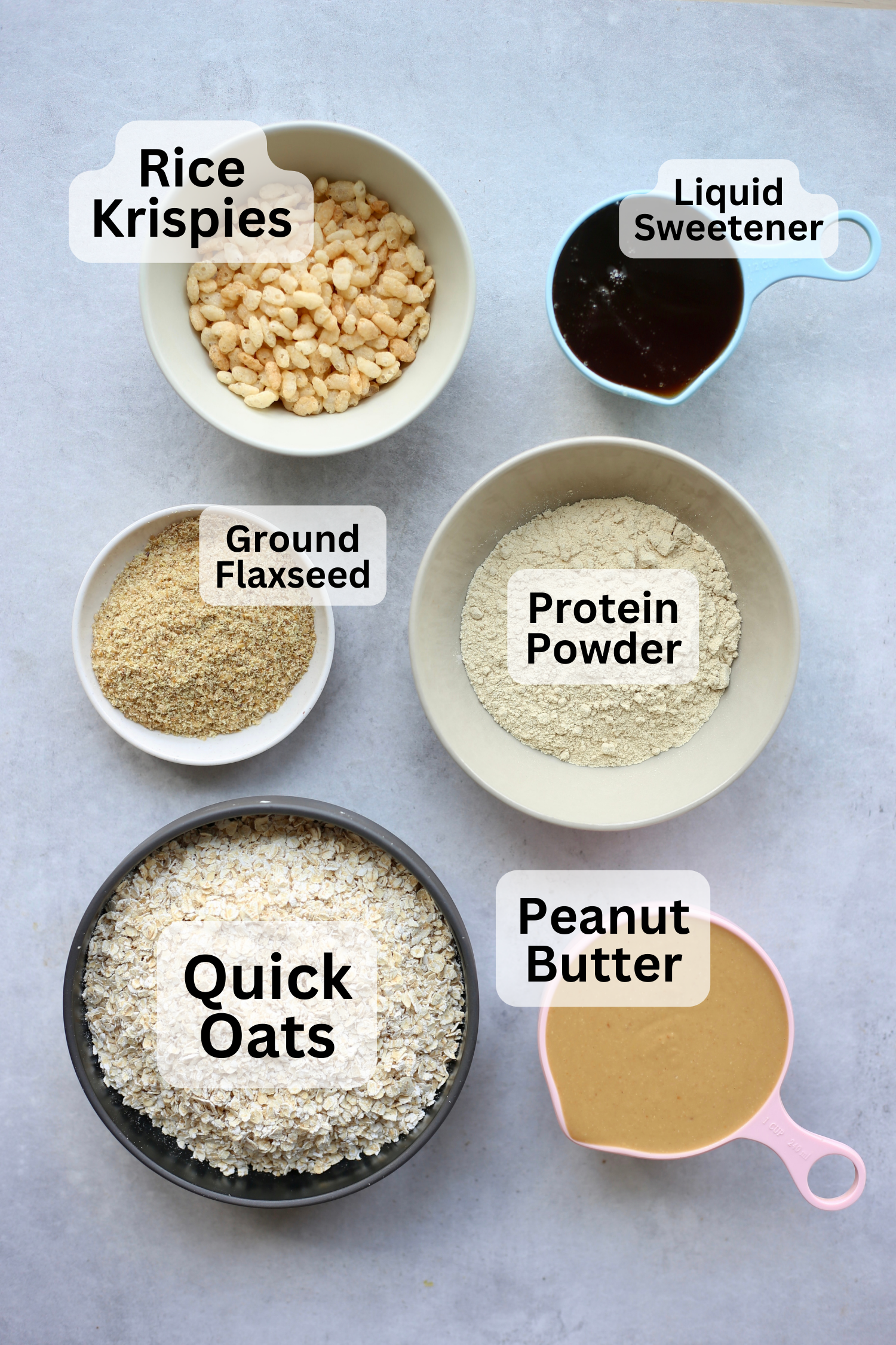 All of the ingredients for vegan protein bars measured out into bowls or measuring cups and laid out on a table. 