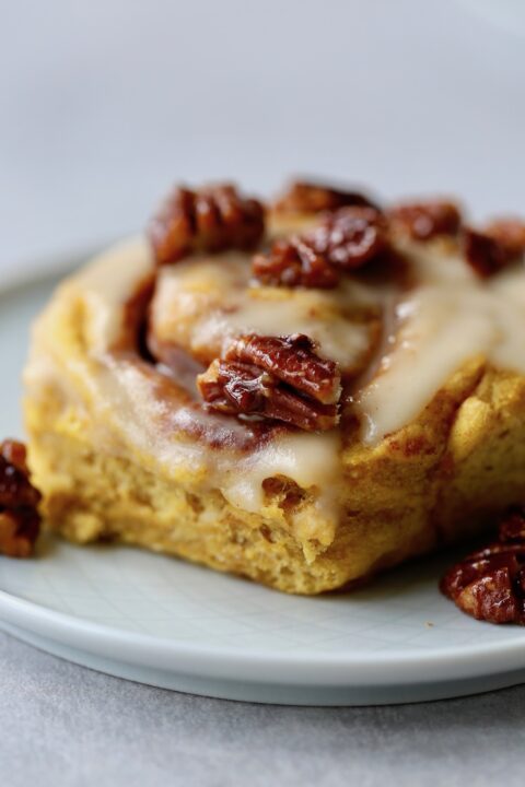 Vegan pumpkin cinnamon rolls topped with candied pecans!